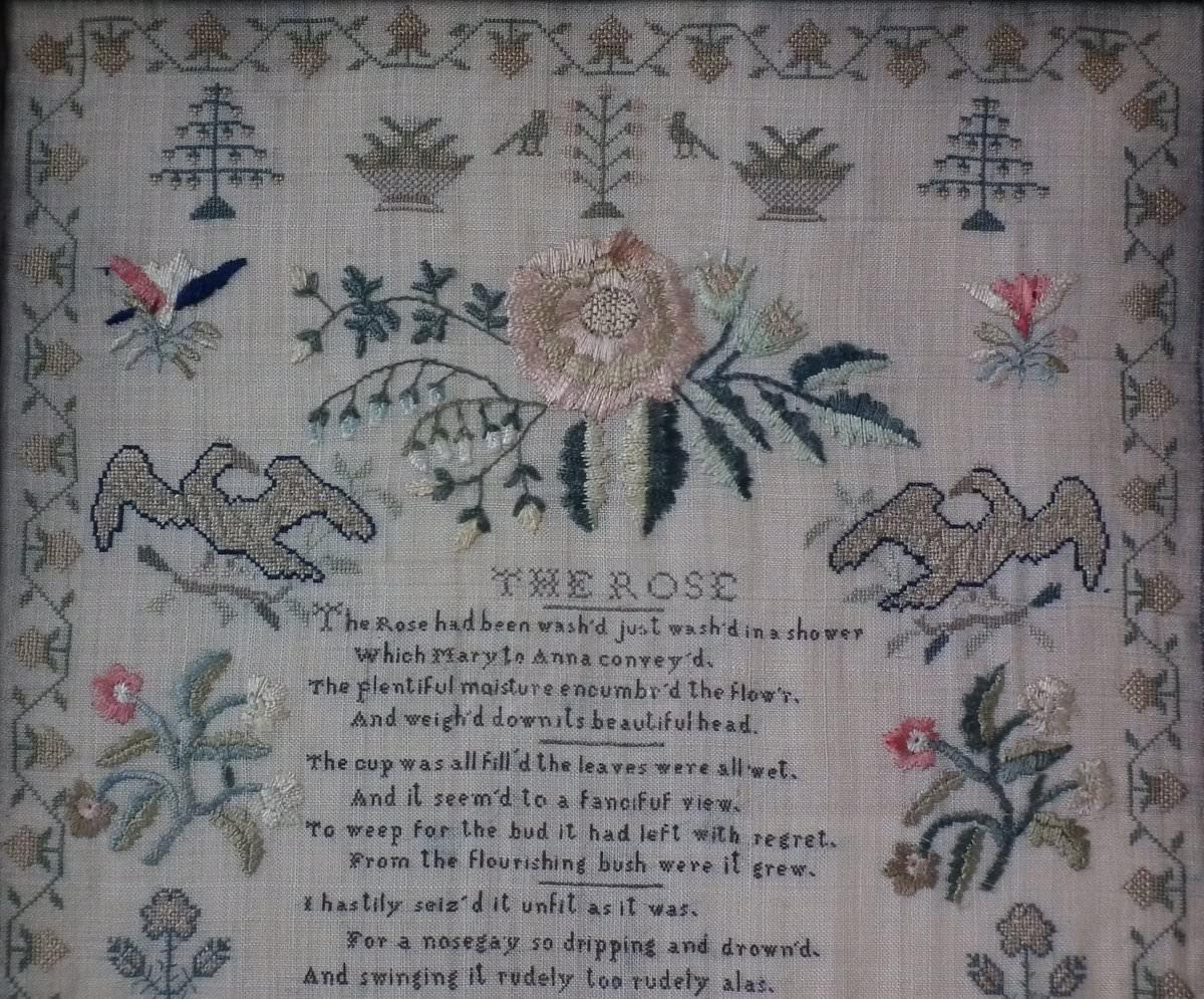 1838 Sampler by Mary Ann Sanders. The sampler is worked in silk on linen ground, in a variety of stitches. Meandering strawberry border. Colours greens, cream, yellow, pale blue, white, pink and blue. Verse entitled 'THE ROSE' reads, the Rose had