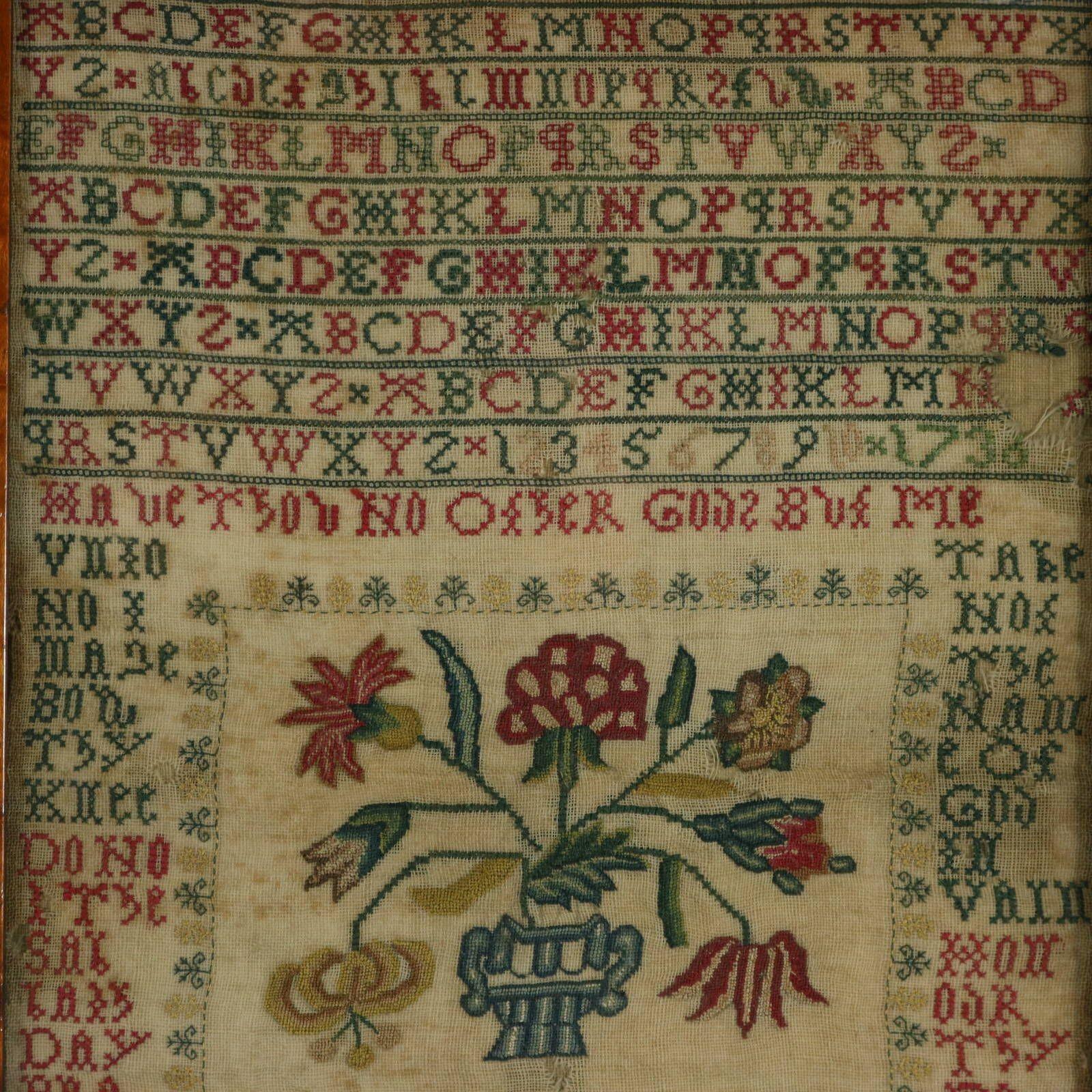 George II period Sampler Stitched in 1736. Possibly of Scottish origin, suggested by the following characteristics: predominant green and red colouration, curlicues bordering the central flowers motif and the peacock with a 7 branched tail. The