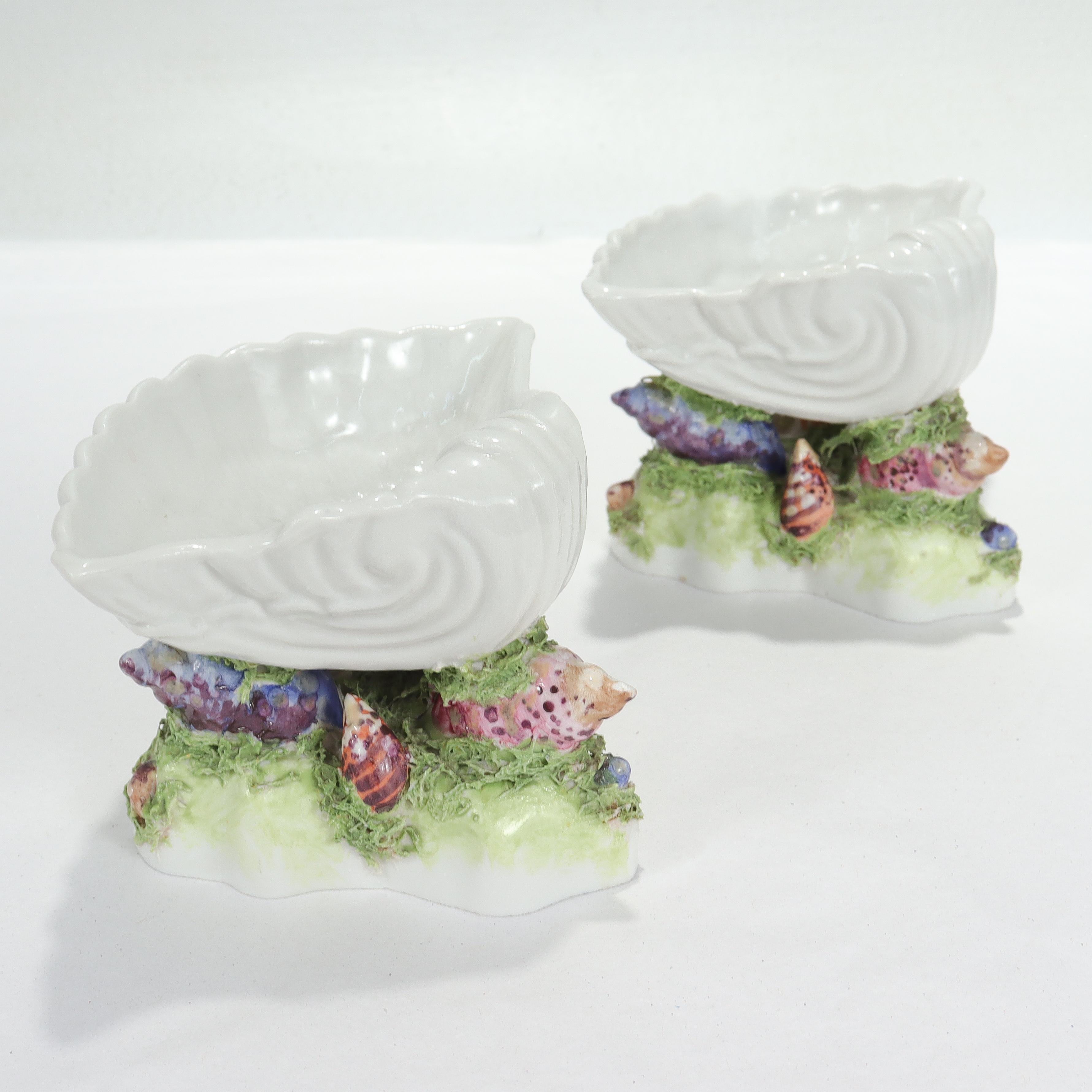 A fine pair of antique figural porcelain sweetmeat dishes or footed bowls.

By Samson.

Each having the form of a white scallop shell set atop column of polychrome shells and green seaweed and a shaped foot.

Mimicking the style of Worcester