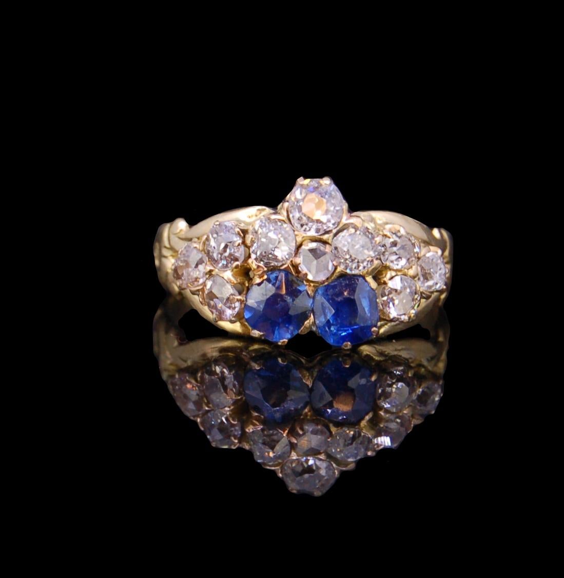 ANTIQUE SAPPHIRE AND DIAMOND RING, the center designed as a stylized viola with 2 blue sapphires and 4 diamonds, flanked on each shoulder by a cluster of 3 diamonds. The sapphires totalling approx. 0.60 ct. The diamonds totalling approx. 1 ct. Size
