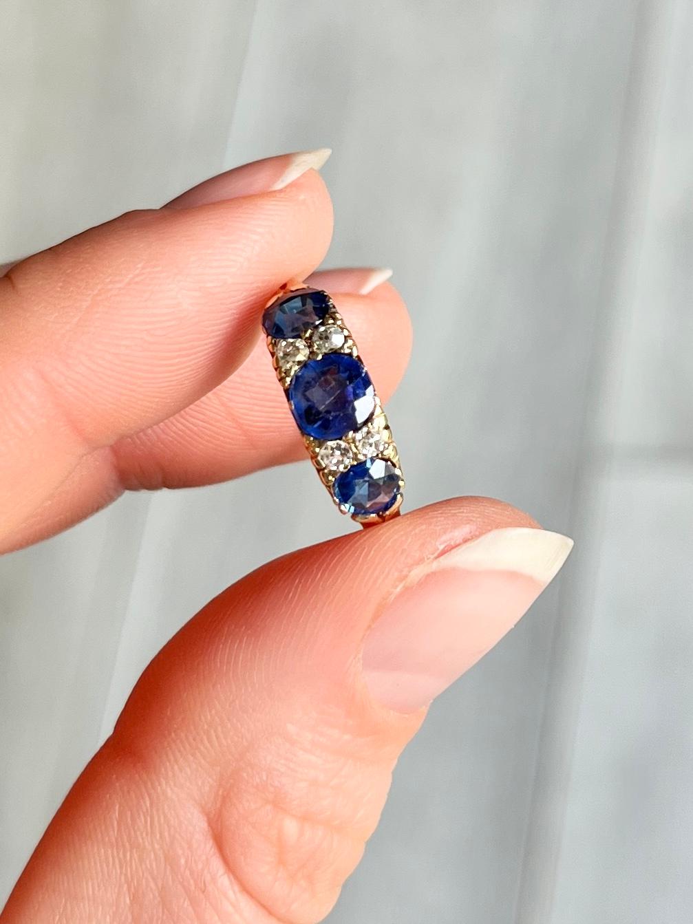 This gorgeous ring dates to the early 1900's and holds three inky blue sapphires. The central sapphire measures 60pts and the ones either side measure 30pts each. In between the blue stones are pairs of diamonds measuring 8pts per pair. The ring is