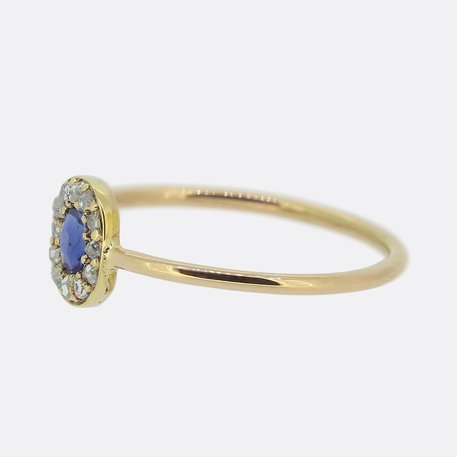Aquí tenemos un delicioso anillo en racimo de zafiros y diamantes. Esta pieza data originalmente de la época victoriana y la cabeza luce un único zafiro redondo facetado de un vivo tono azul medio. Una hilera de diamantes talla rosa rodea esta rica