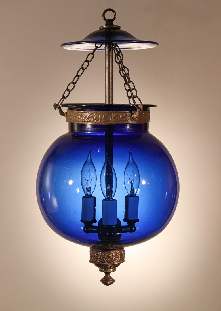 A gem in our bell jar collection, this circa 1870 antique English globe pendant features striking sapphire blue hand blown glass that is embellished with all-original brass fittings. The lantern, which was originally lit with a candle, has been