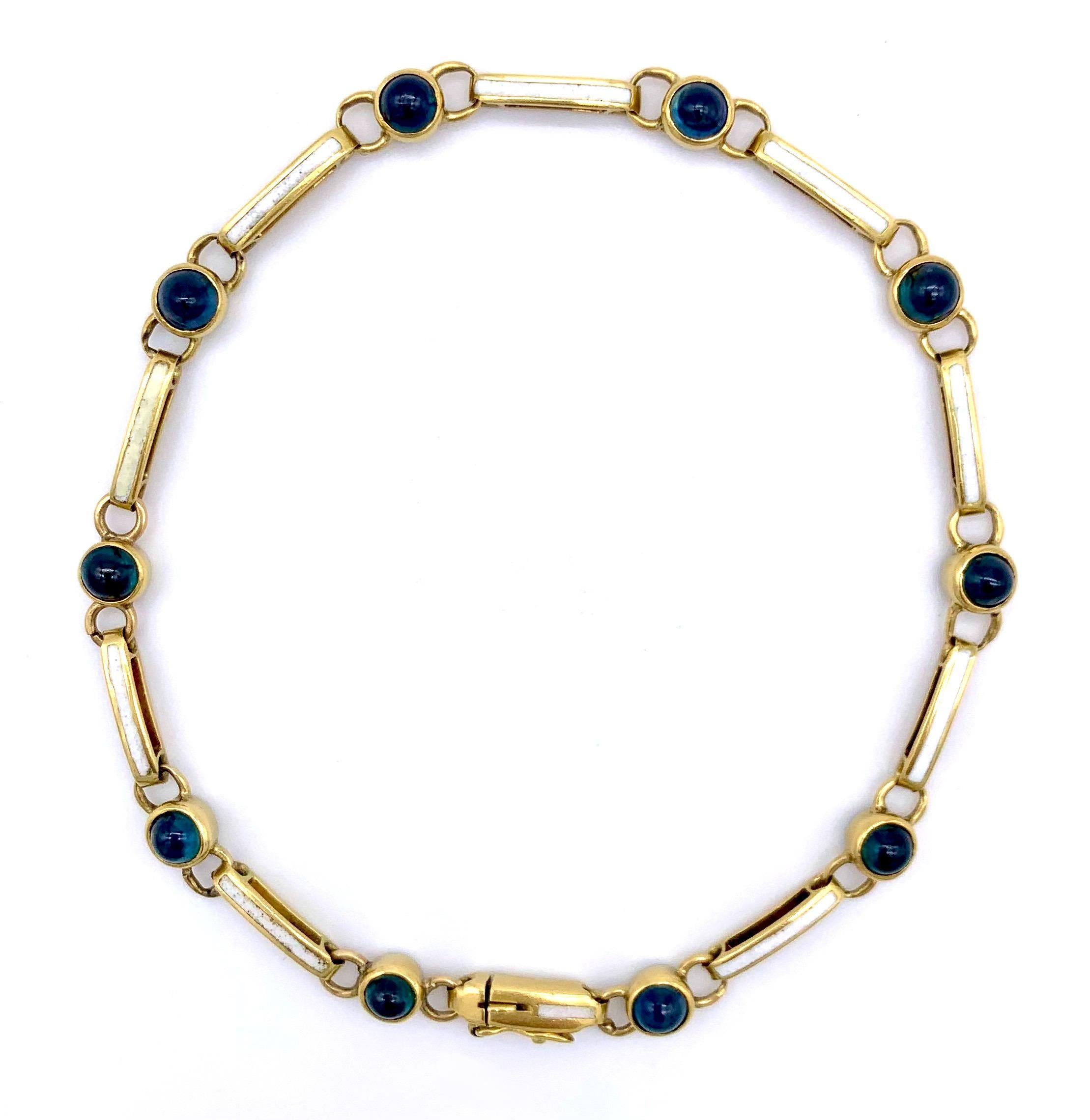 This very elegant 15kt gold bracelet features ten beautiful bright blue sapphire cabochons. They alternate with elongated gold rings that are decorated with opaque white enamel.
The bracelet is signed with makers initials. 