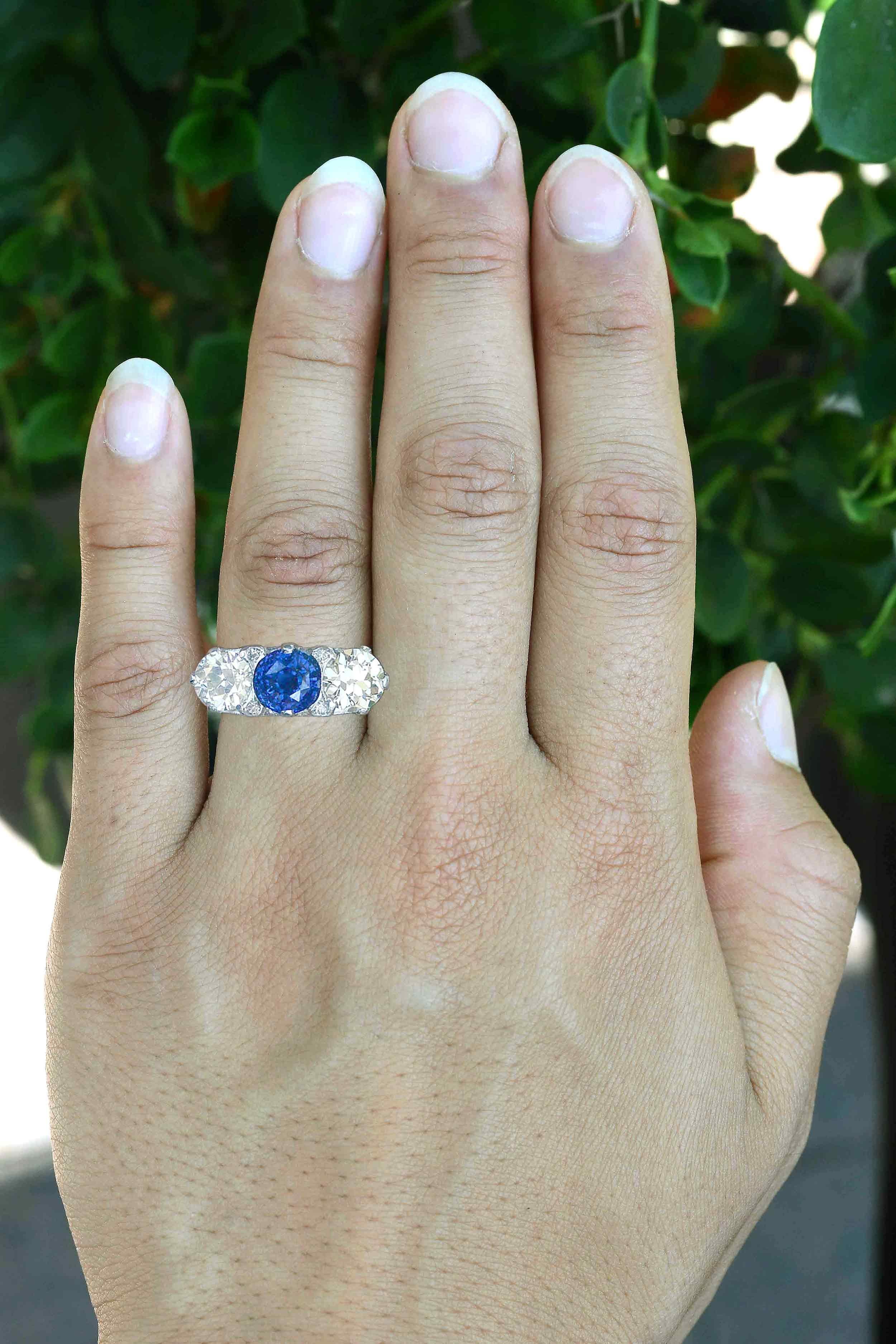 A magnificent antique sapphire and diamond 3 stone engagement ring.  Boasting a pair of gloriously brilliant old European cut diamonds, together weighing nearly 3 carats, centered by a velvety blue natural sapphire caressed in an amazing filigree