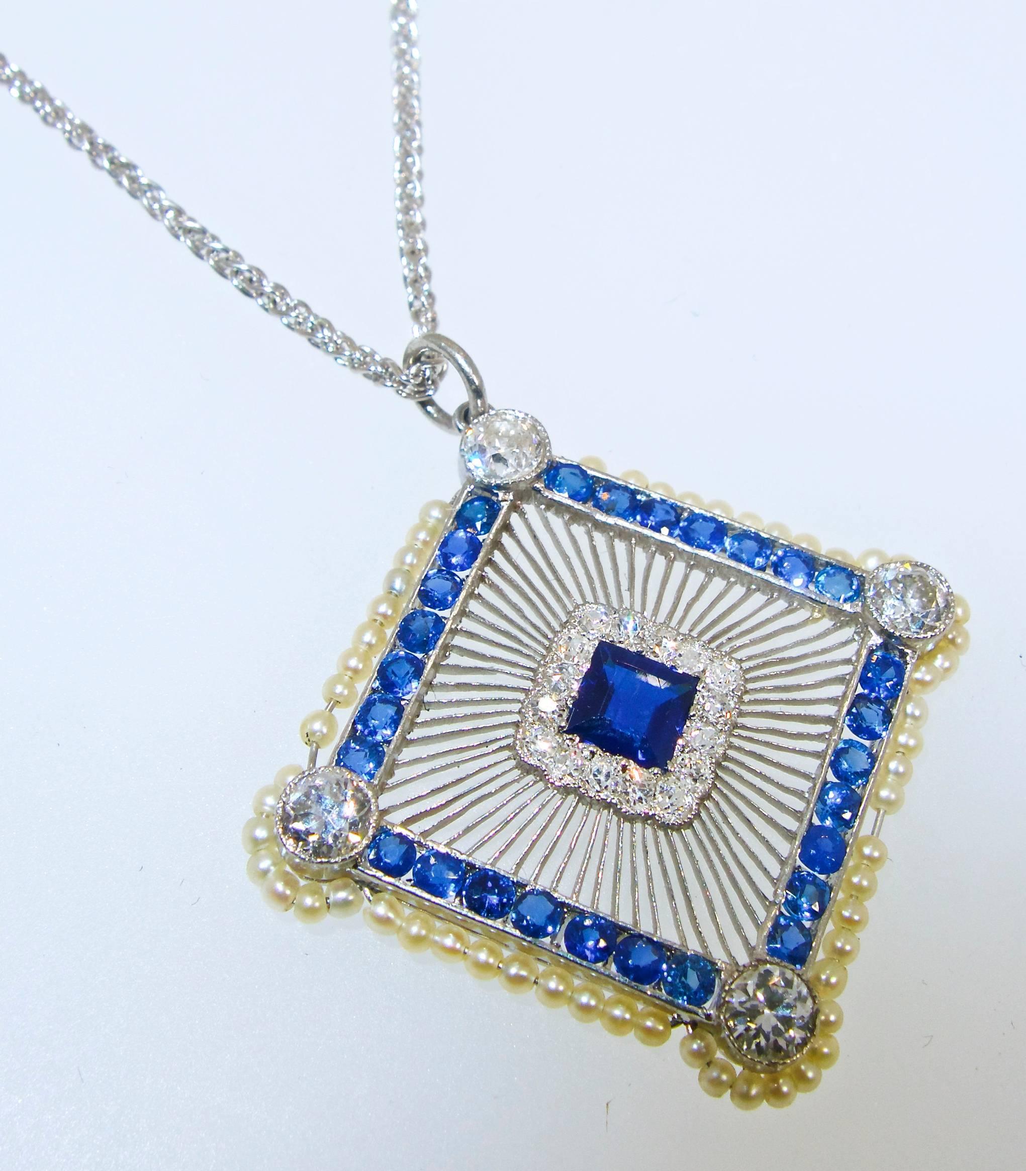 Circa 1915, Edwardian platinum pendant possessing just over .70 cts of small diamonds and 29 fine blue natural sapphires weighing totally just over 2.0 cts.  The pendant, which is bordered with natural small seed pearls, is .75 inches wide and 1.0