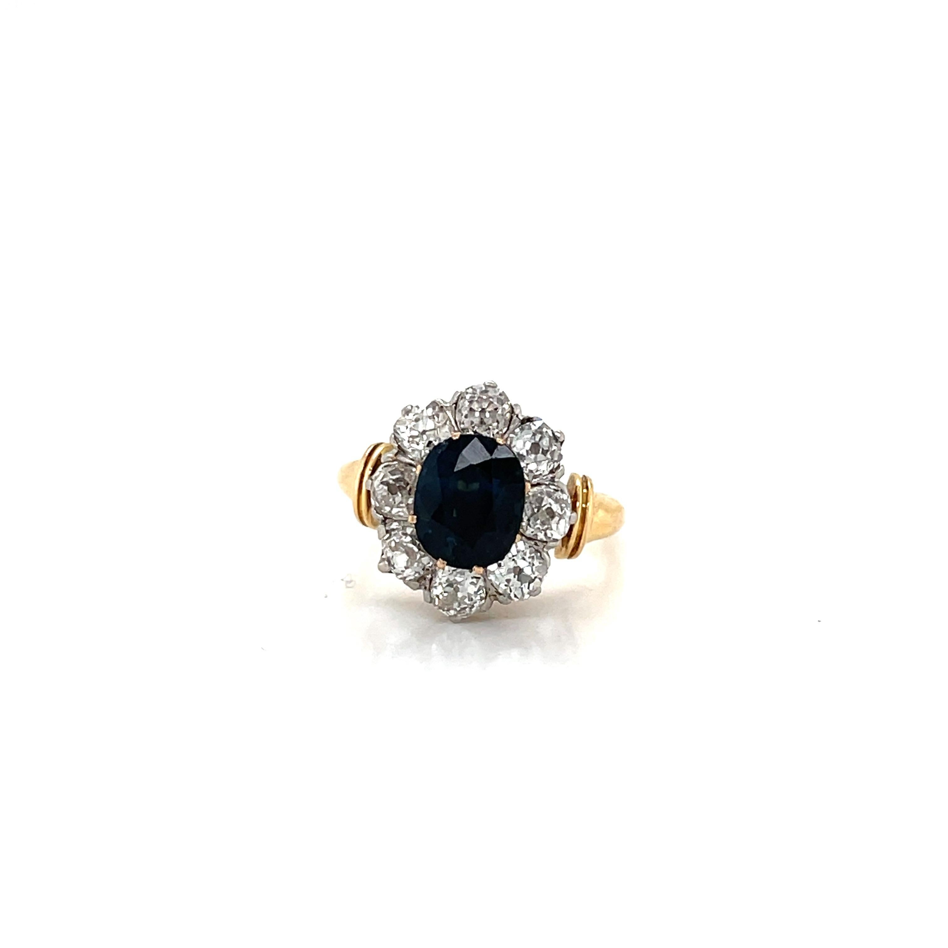 Beautiful 18k yellow gold and platinum cluster ring. It features in the center one vivid Natural Sapphire oval shape, origin Australian, weight 2,20 ct, surrounded by Sparkling Old mine cut diamond weighing 1,60 ct. all together, graded H color Vs