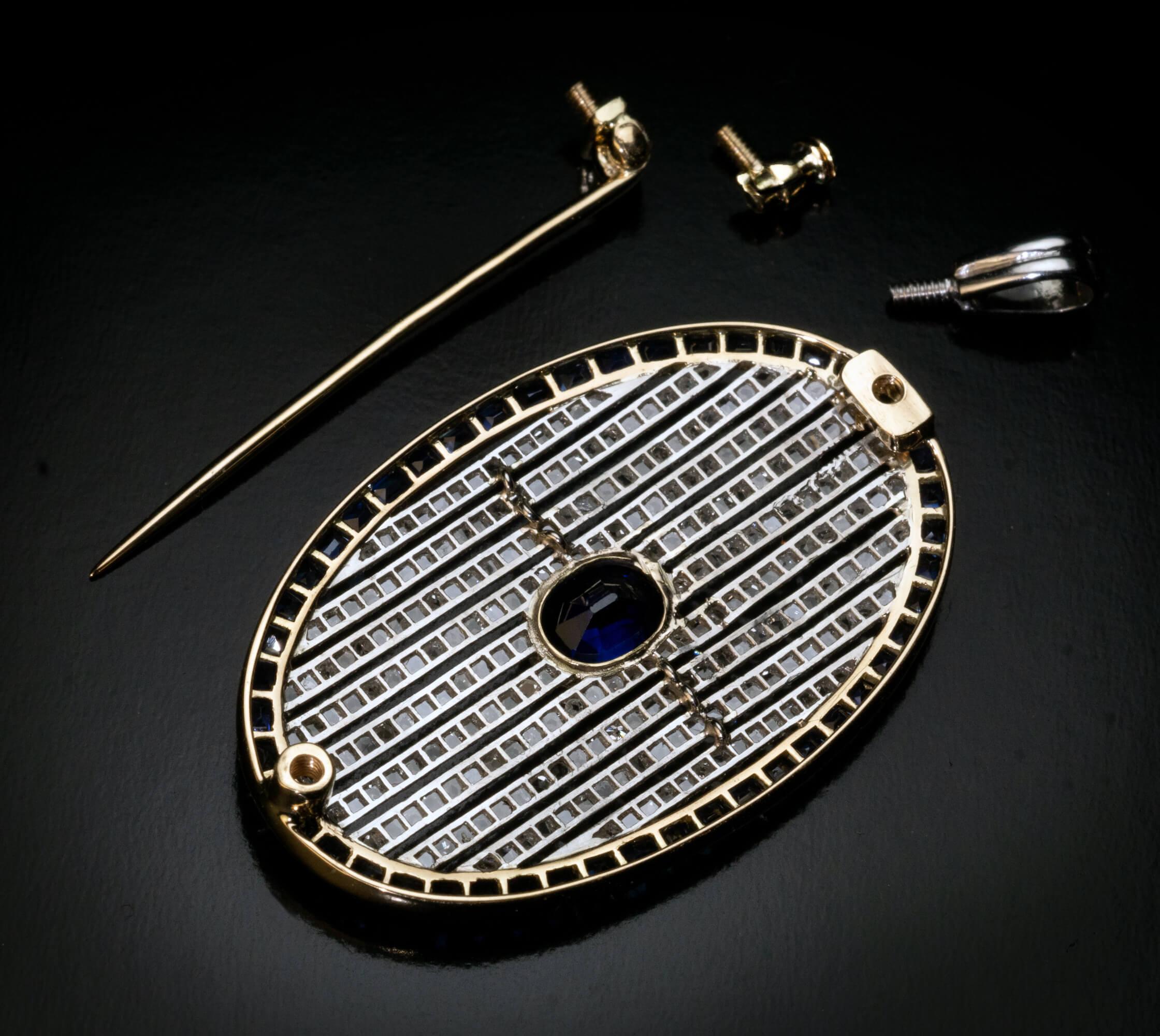Circa 1910  This antique convertible brooch / pendant is finely crafted in yellow 14K gold and platinum. It features an excellent royal blue sapphire framed with rose cut diamonds within a calibre cut sapphire bezel.  The principal sapphire measures
