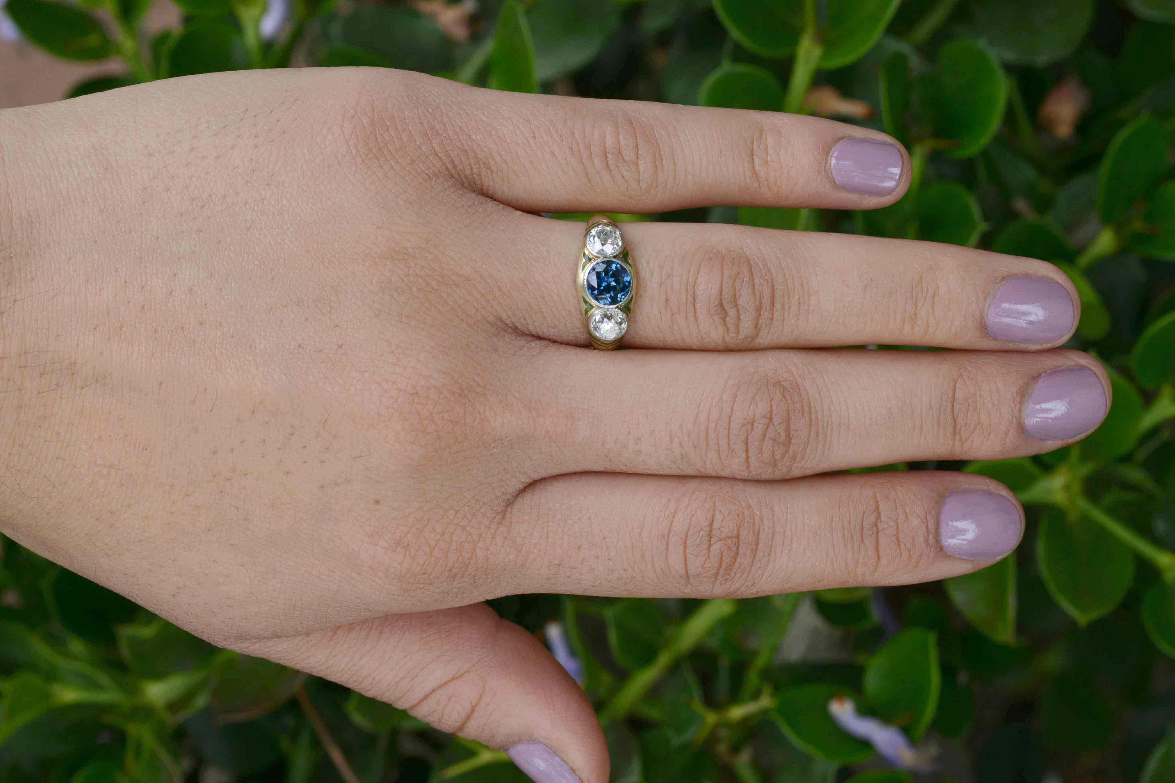 An absolutely enchanting 3 stone sapphire and diamond engagement ring. Dating to the early 1900s Art & Crafts period of the Art Nouveau era, this original antique trinity design boasts a wonderfully lustrous and vivid blue sapphire, flanked by a