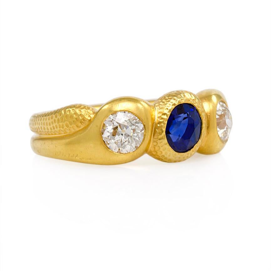 An antique gold stylized and textured three-stone gypsy ring set with a faceted oval cut sapphire flanked by Old European cut diamonds, in 18k.  Signed W.M.  Atw diamonds 0.98 ct.

Top measures approximately 20mm across finger
Current size: US 7 3/4