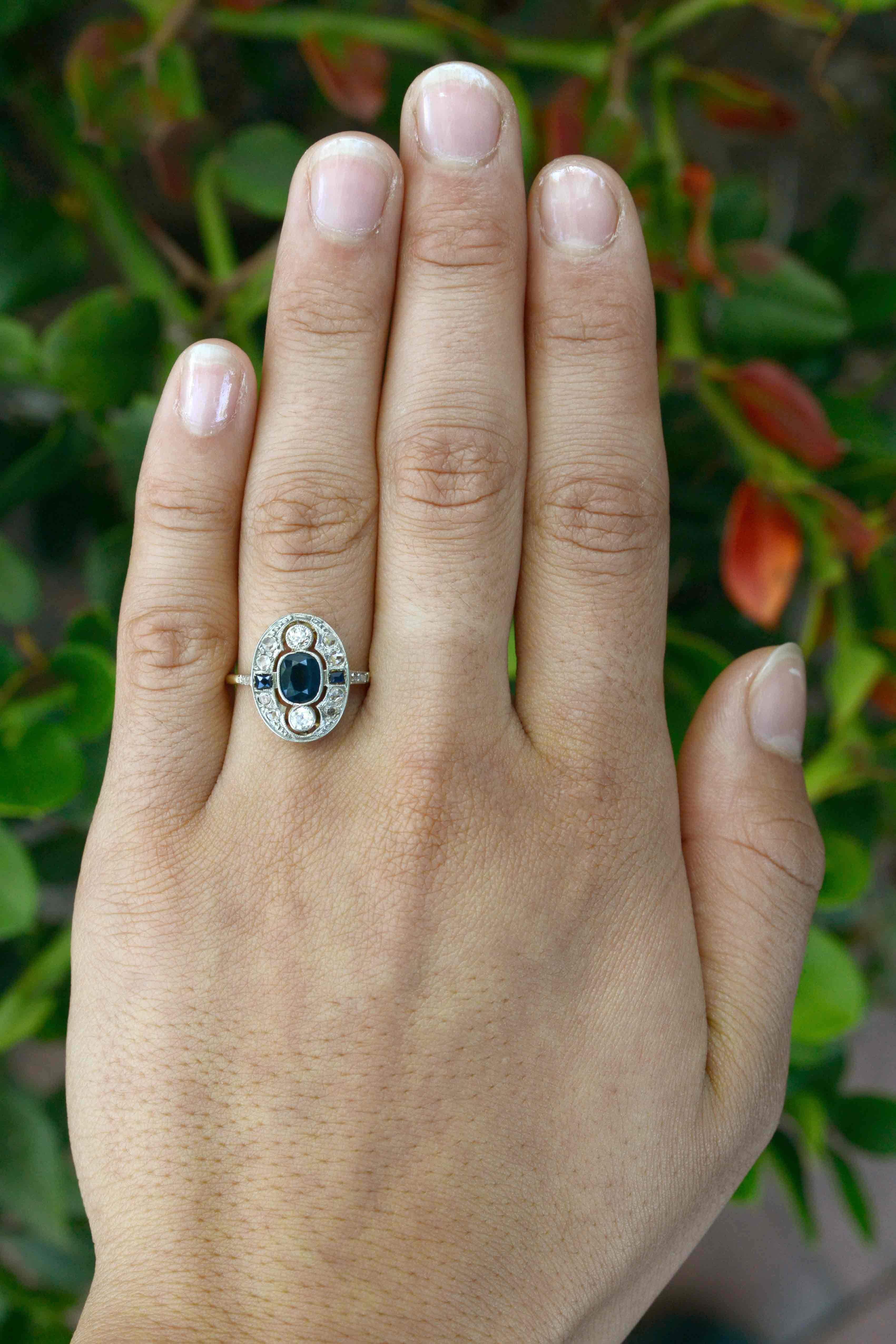 The early 1900s Edwardian era produced some of the most beautiful jewelry. A most intriguing antique sapphire engagement ring that can be an eminently wearable cocktail ring. A velvety, deep navy blue center oval faceted sapphire is flanked by a