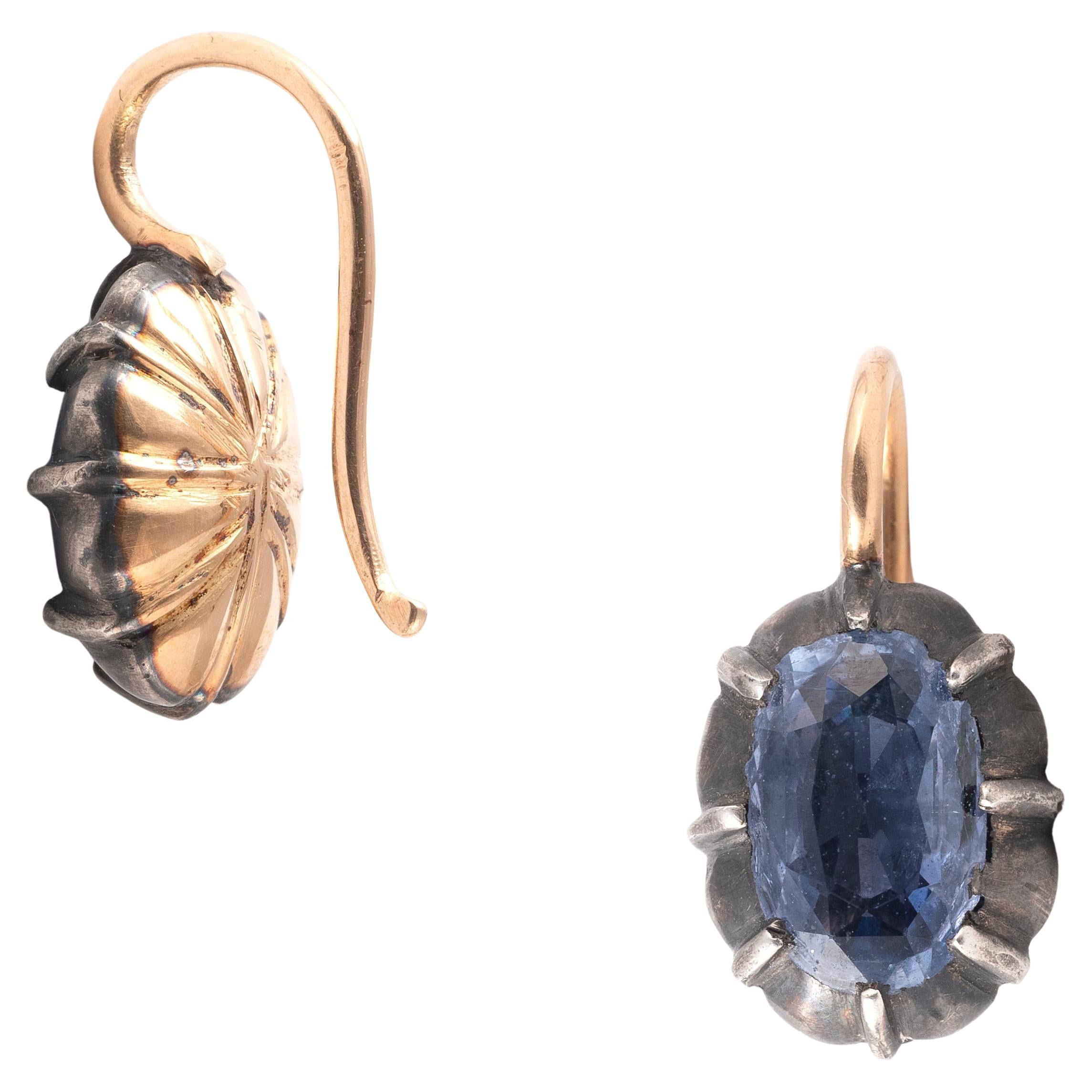 These stunning earrings showcase 2 oval ceylon sapphire  with a total weight of 3.50 carats. They are elegantly set in 18K yellow gold and silver, close on the back. Measuring 18mm long and weighing 4.67 grams, they are perfect for any occasion,