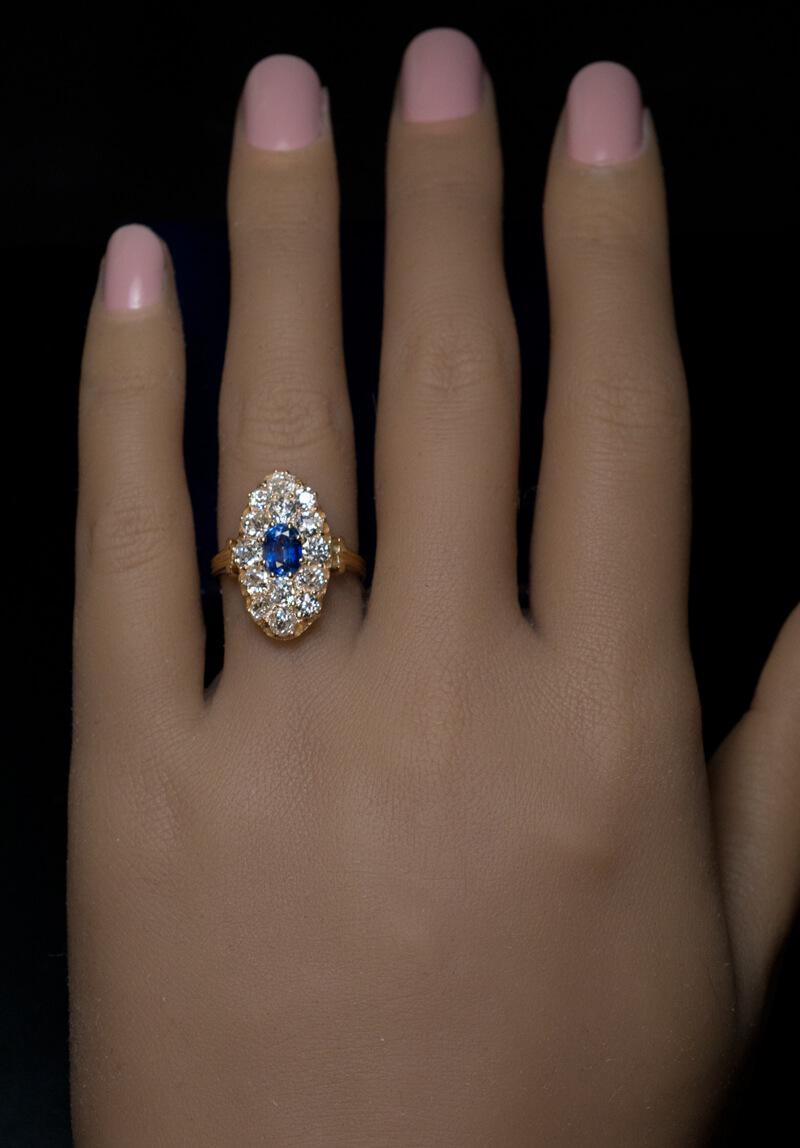 Circa 1890  The 14K yellow gold ring is centered with a 0.89 ct blue sapphire (likely of Ceylon origin). The center stone is surrounded by chunky old mine cut diamonds (G-H-I color, VS-SI clarity).  Estimated total diamond weight is 1.60 ct.  The