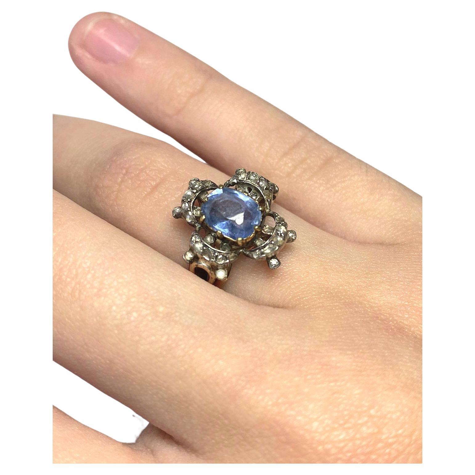 Antique ring in artnovo style centered with violet blue sapphire colour diameter of 6.60mm×6mm in 14k gold setting topped with silver artnovo designe prongs with rose cut diamonds ring dates back to europe early 19th century 