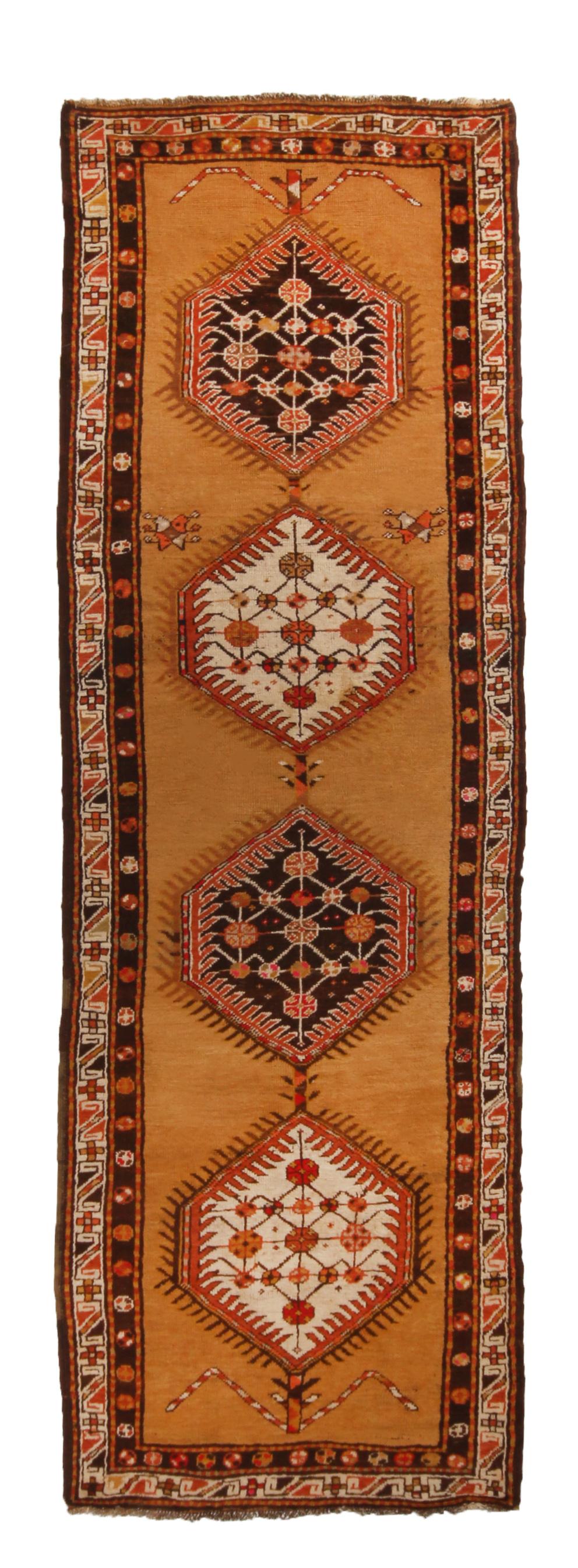 Originating from Persia in 1900, this antique Sarab runner enjoys a unique alternation of beige, red, and black colorway in its field medallions against a bright abrash copper-orange background. Hand knotted in high quality wool, it is unique to see