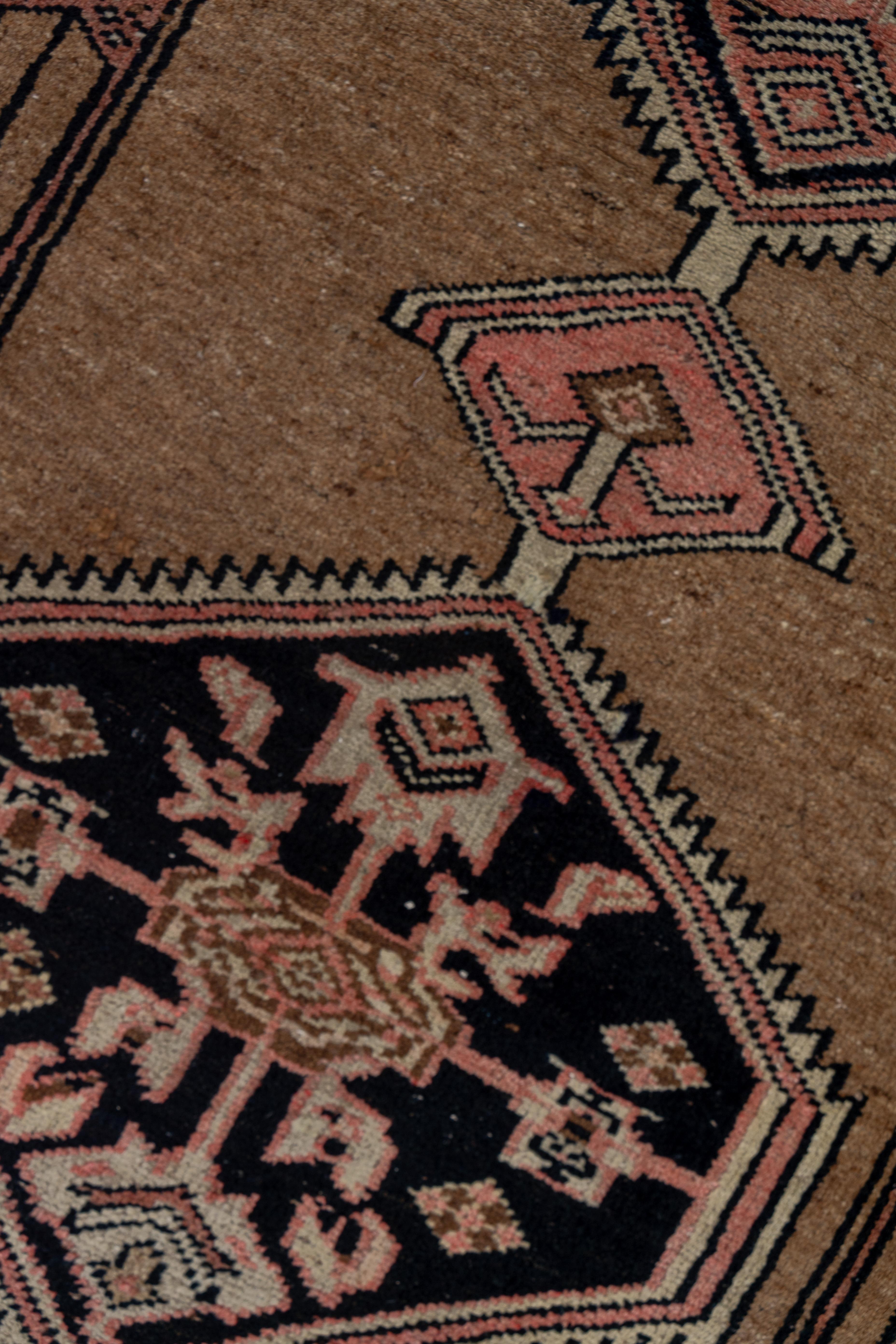 The camel-tone open field displays a pole medallion of six black serrated hexagons, each enclosing a palmette cruciform. The camel tone borders are plain, display reversing simple palmettes or long cartouches with single flowers.