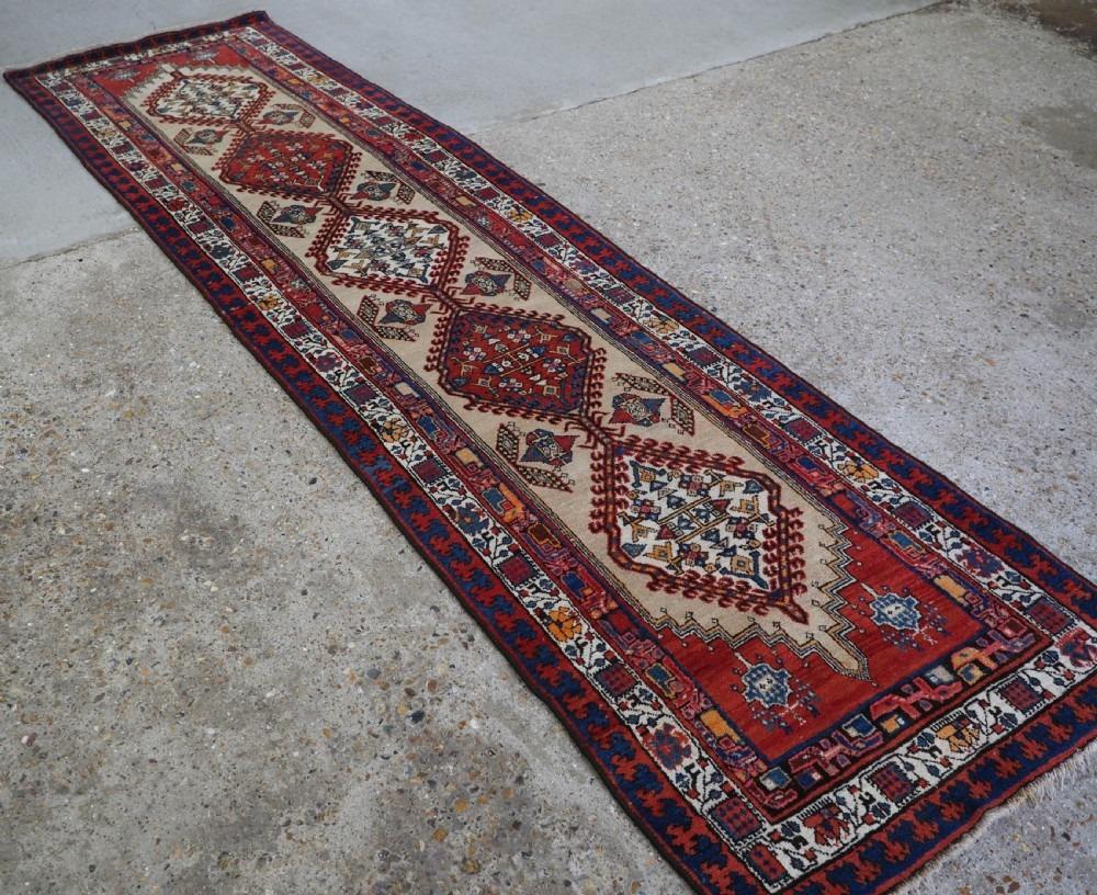 Antique Sarab village runner with a camel wool ground with a very colourful linked medallion design and traditional border
Circa 1920

The runner is in excellent condition with slight even wear and good pile

The runner is suitable for normal