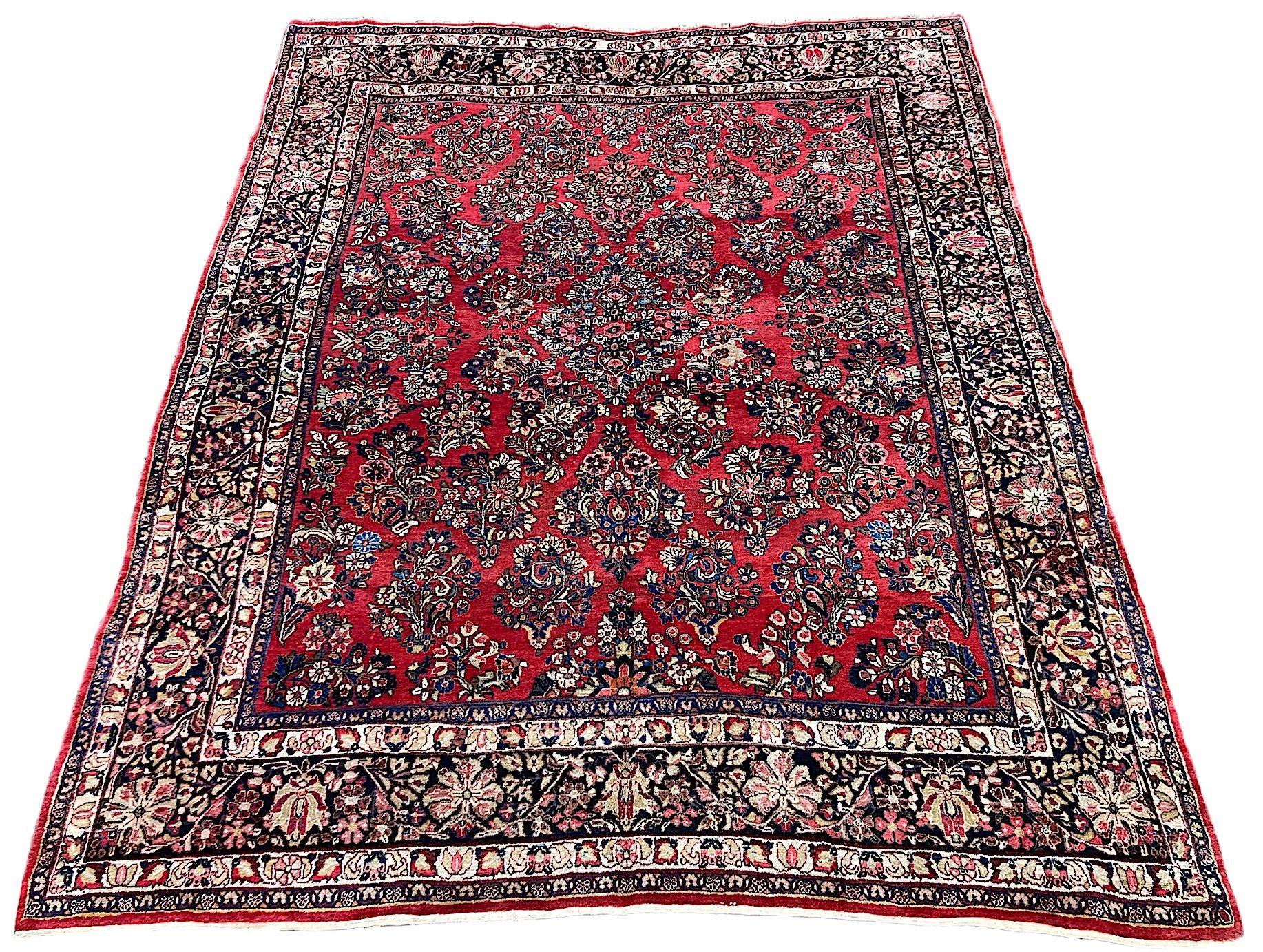 A fabulous antique Sarouk carpet, hand woven circa 1920. The carpet features an allover design of flower bouquets on a terracotta red field surrounded by a charcoal border. Finely woven with soft wool and lovely secondary colours of greens, pinks