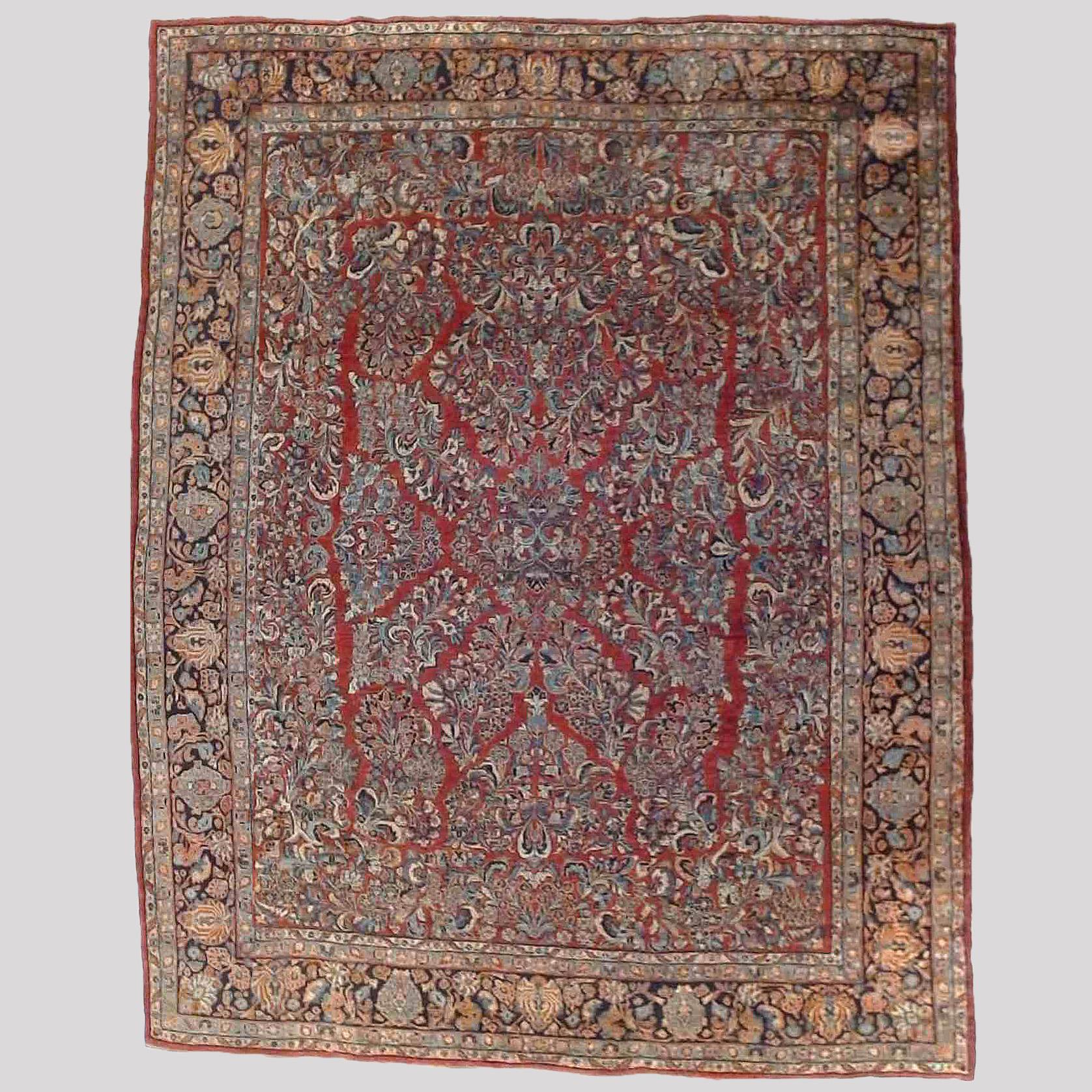 An antique Sarouk oriental rug offers wool construction with allover floral and foliate design on red ground, c1930

Measures- 134''L x 107.5''W 