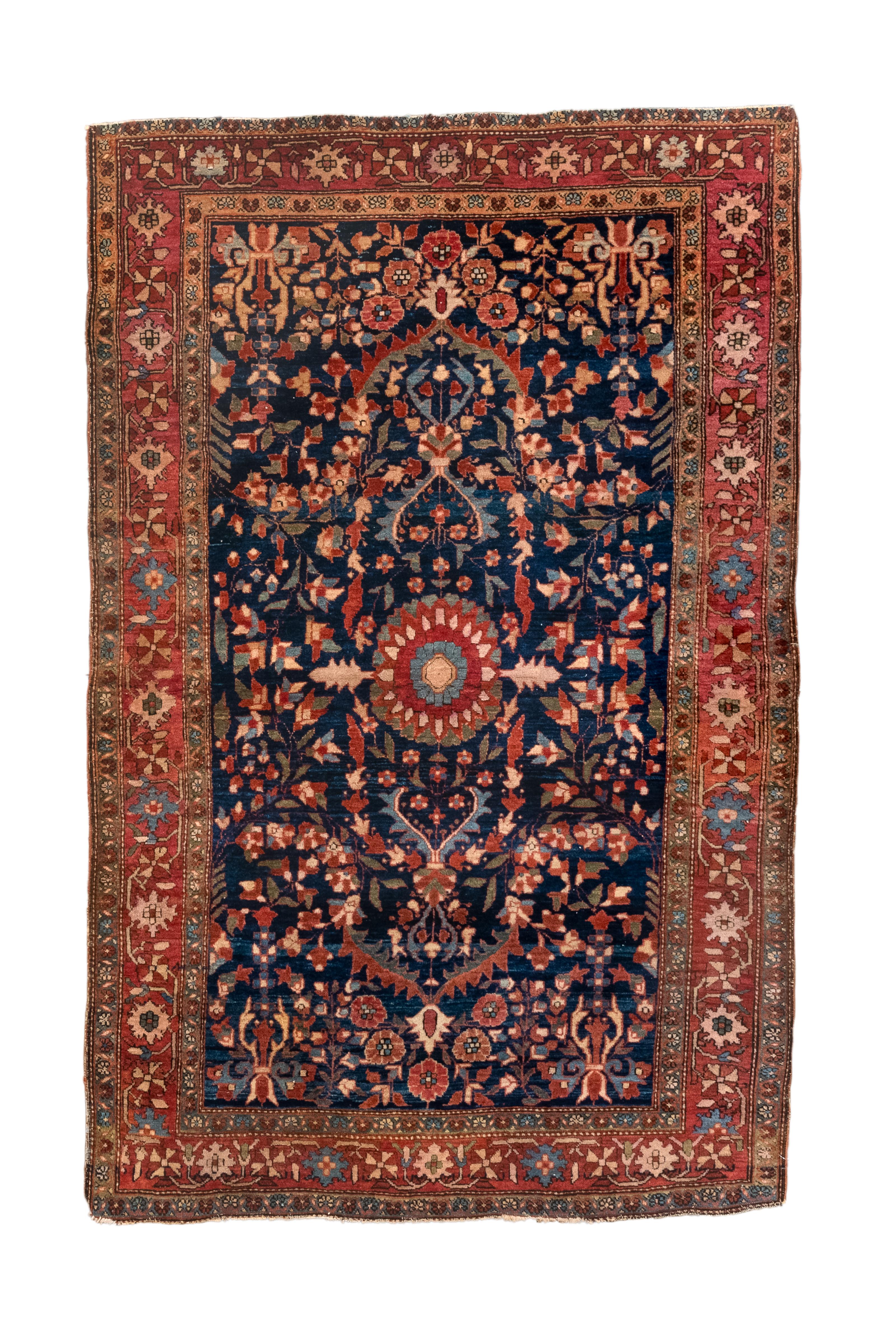 De la période de l'entre-deux-guerres, cette pièce bien tissée sur coton avec des nœuds asymétriques présente un médaillon rond à pétales rouges avec un sous-médaillon à pétales bleu clair à l'intérieur.  Les fleurs tourbillonnent et des arcs sont