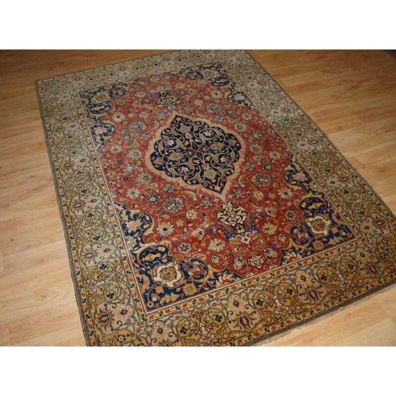 An antique Persian Sarouk rug of classic small medallion design, with floral sprays on an terracotta red ground. This is a classic example of a Sarouk rug, well drawn with good colour. The deep indigo blue medallion stands out well on the soft red