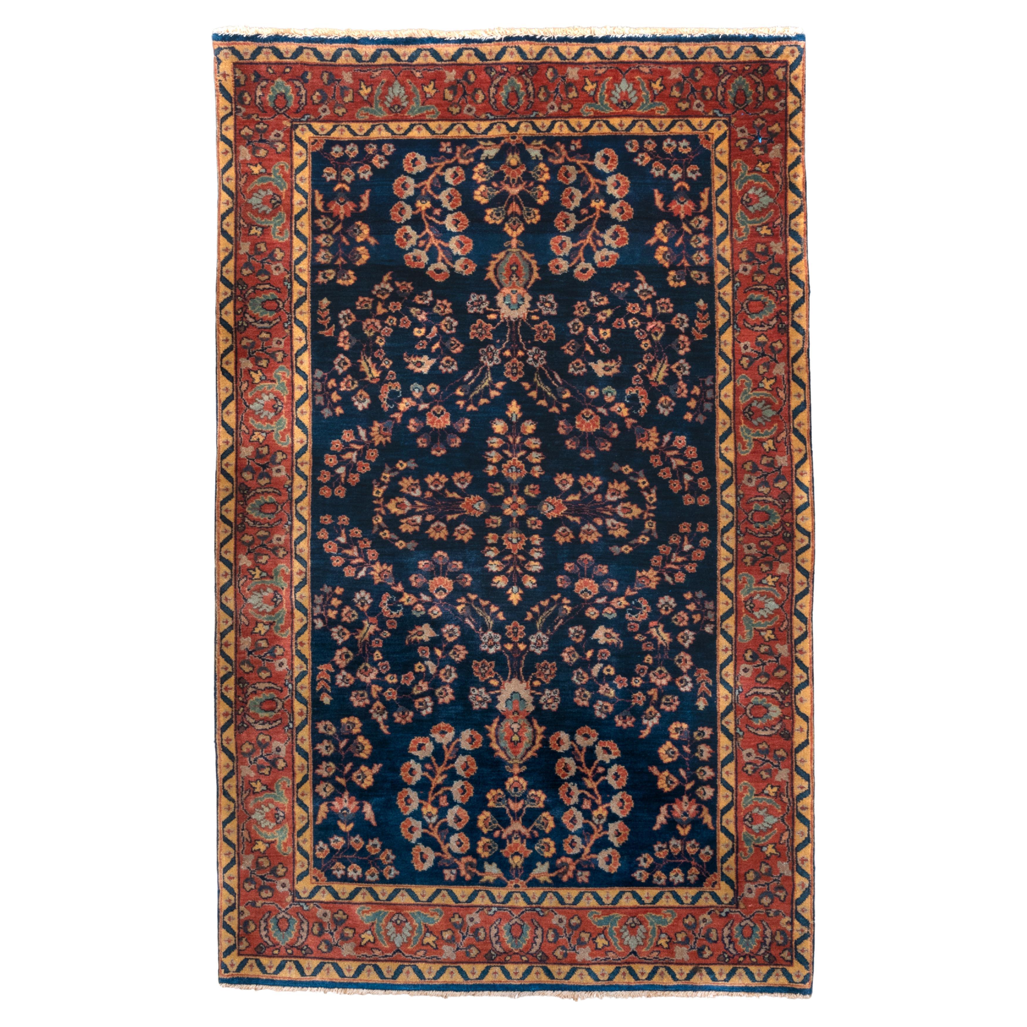 Sarouk antiguo con fondo azul marino y borde rojo en venta