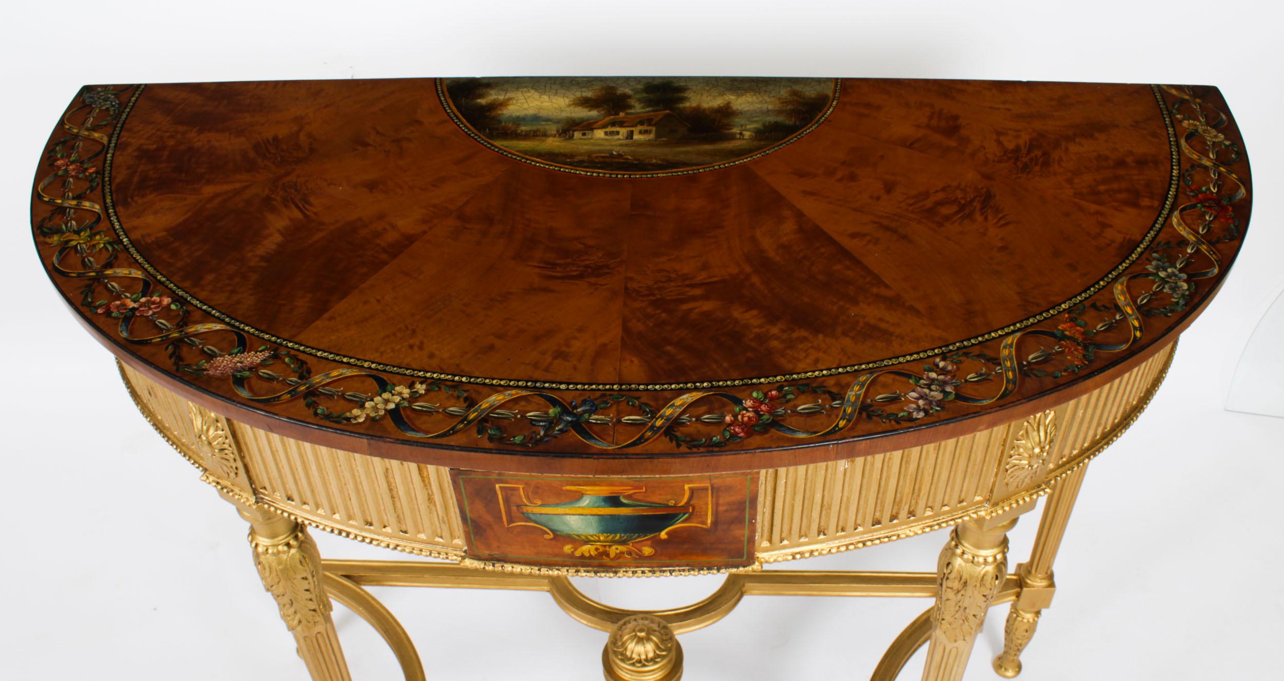 This is a elegant antique satinwood hand painted giltwood demi-lune console table , Circa 1880 in date.
 
The demi lune top beautifully painted in the manner of Angelica Kauffman and features a landscape scene with a picturesque cottage and a