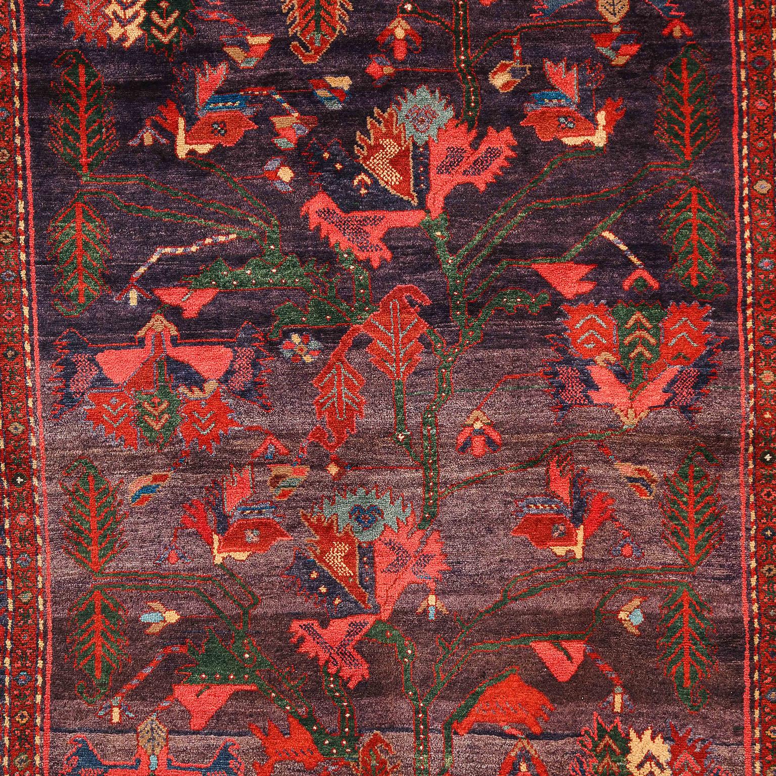 Ce tapis persan antique Design/One, vers 1910, noué à la main en pure laine filée, présente un motif unique d'arbre de vie. Composé d'un champ général et d'une bordure à plusieurs couches, les teintures végétales organiques ont produit les riches