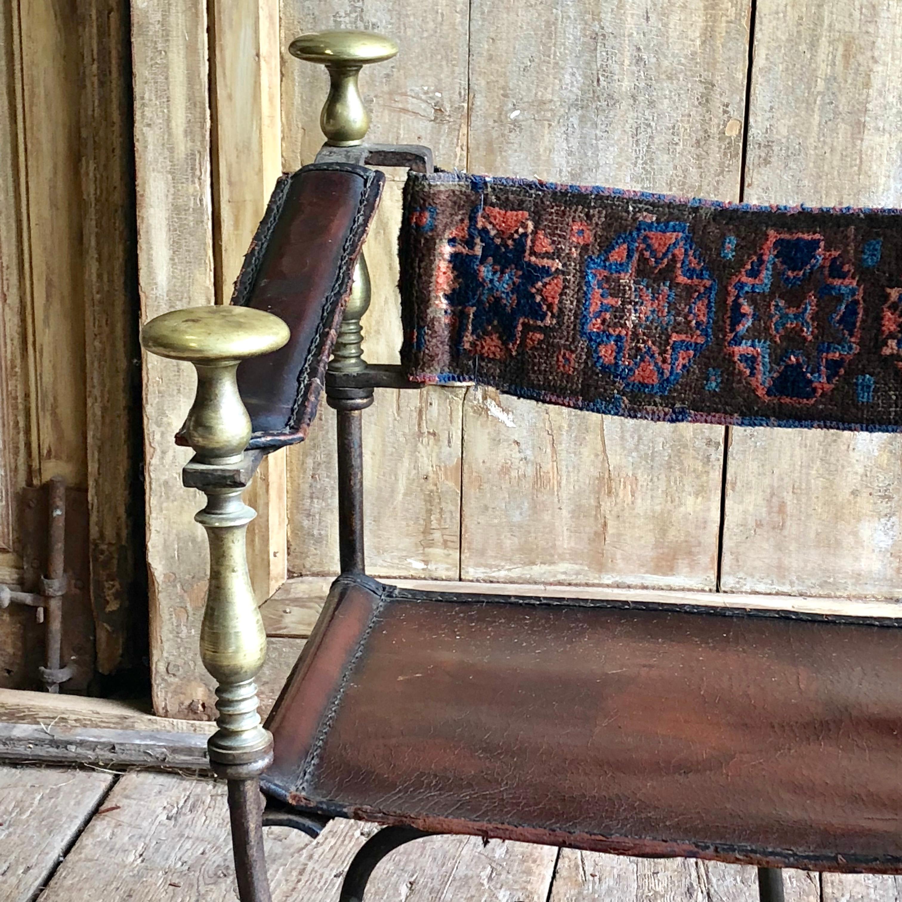 An antique Spanish or Italian Savonarola chair in wrought iron with brass accents, 19th Century.
Handstitched leather seat and arm rests with a tapestry backrest. The chair folds for transport. Traces of older gilded finish on iron. Lots of