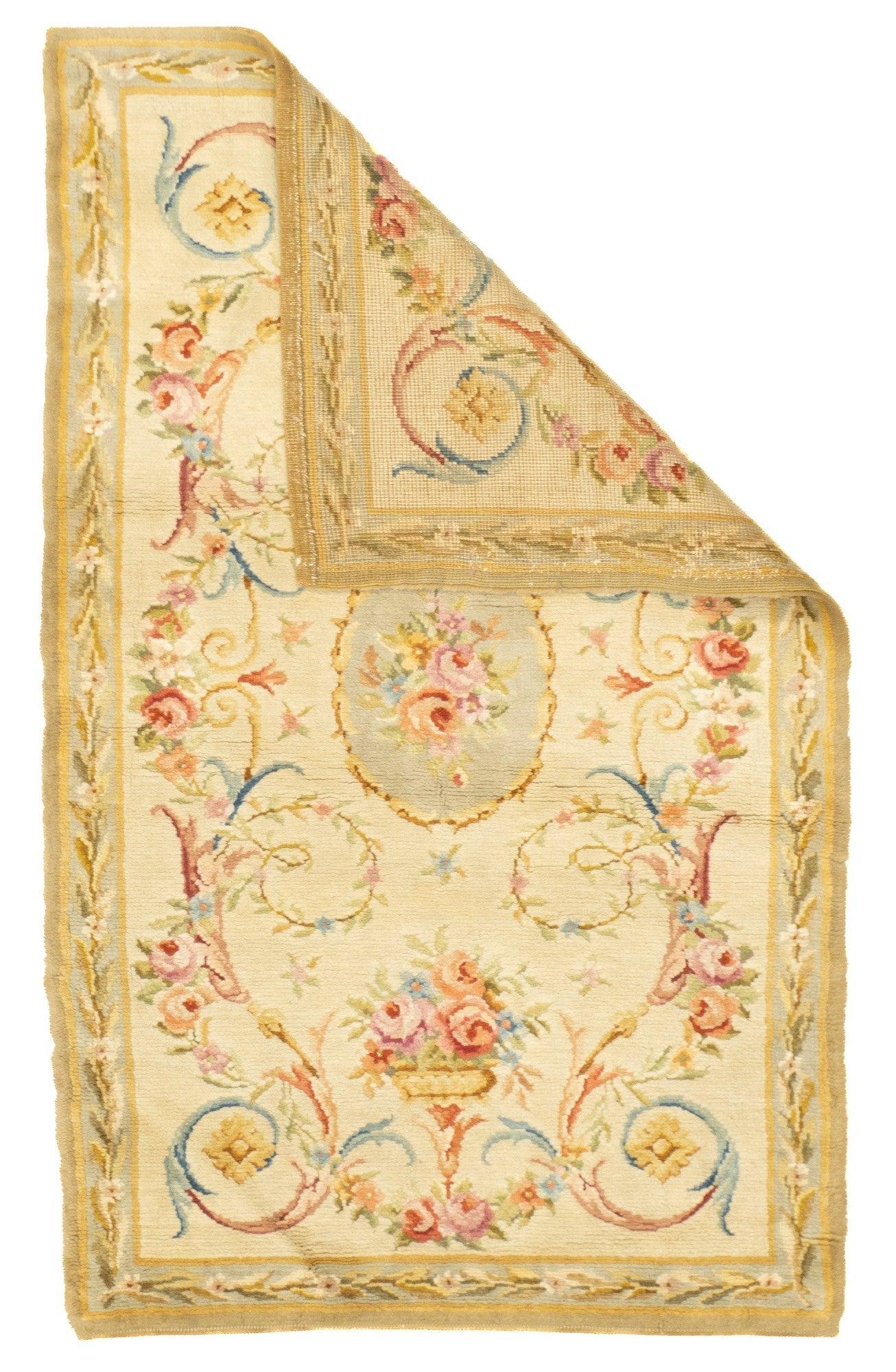 Antique Savonnerie (One of pair) Rug 3'2'' x 5'2''. In the Louis XV style, with a straw-ecru field centred by a rose bouquet. Acanthus and rose volutes. Baskets of roses at the field ends. Laurel leaf trail main border. Thick pile, moderate/coarse