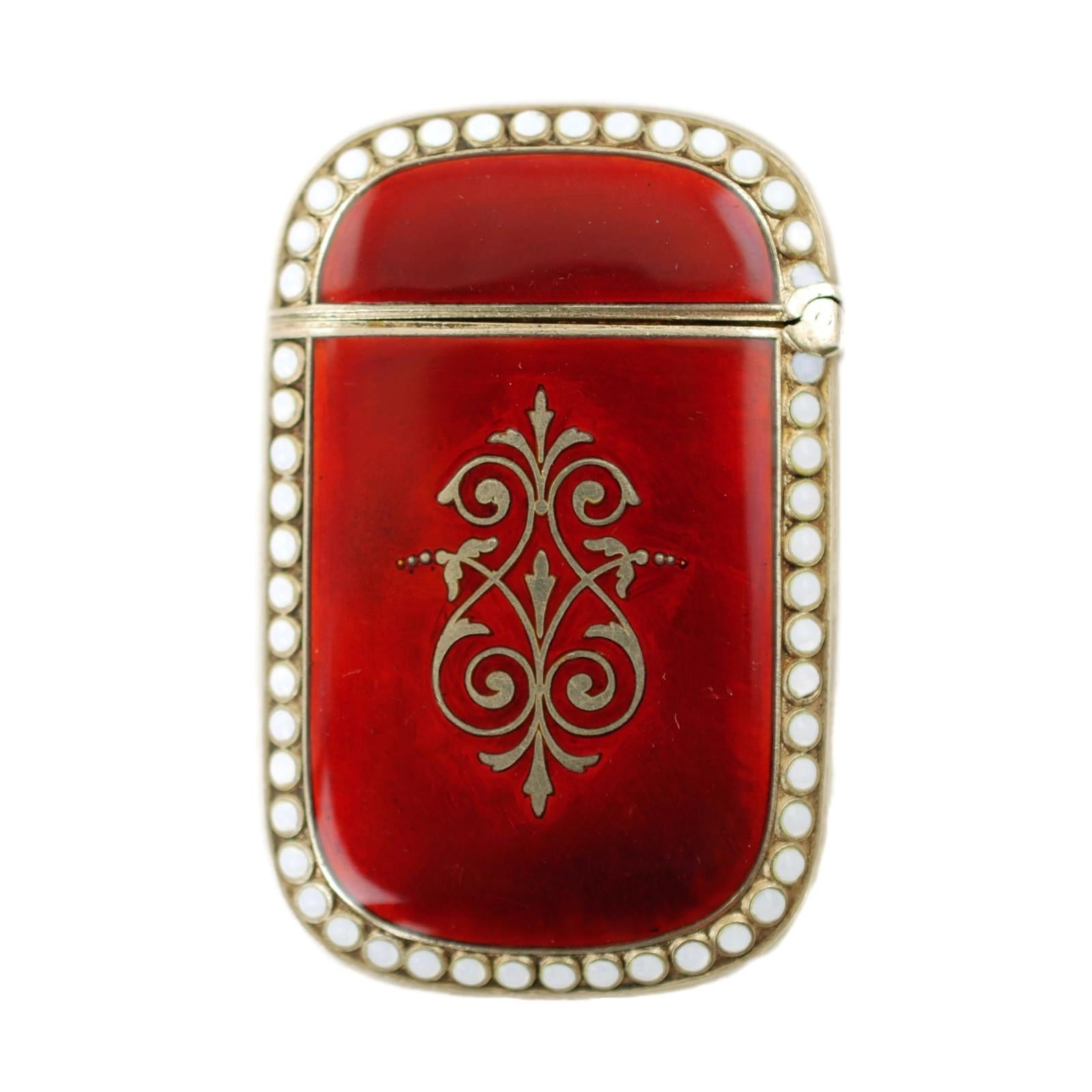 This highly collectible circa 1896 vesta case was made in Oslo, Norway by Arthur David-Andersen. The match safe has a hinged lid and is composed of sterling silver with a vermeil wash. The exterior features crimson enamel decoration with large,