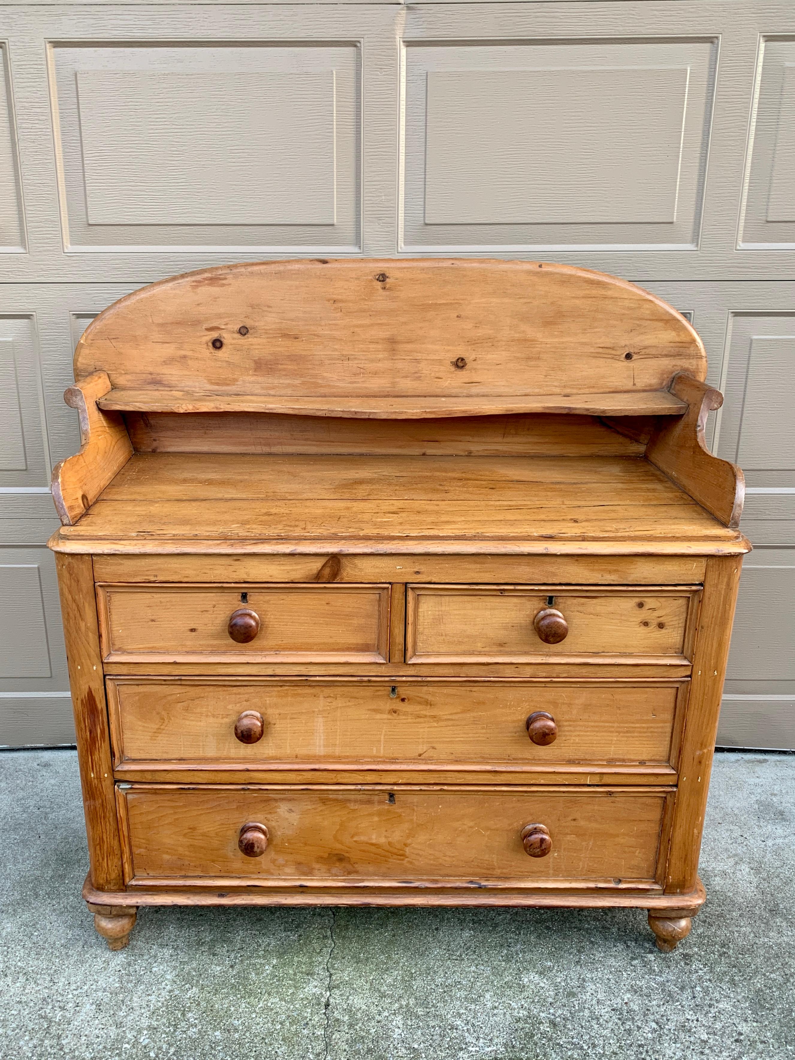A stunning and unique Scandinavian solid pine four-drawer dresser, chest of drawers, or server. This beautiful piece is all original, including the knobs and curved back.. It would be right at home in a traditional space or a modern room. With