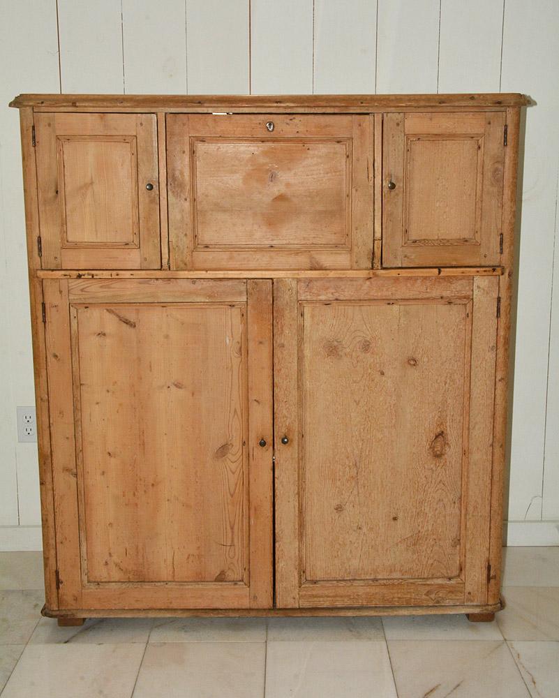 Wonderfully rustic pine cupboard. Can be used for linen, kitchen or where ever extra storage is needed. Three compartments at the top. Center door opens down. Lower part with 2 larger doors and shelving in the interior. Graceful lines.