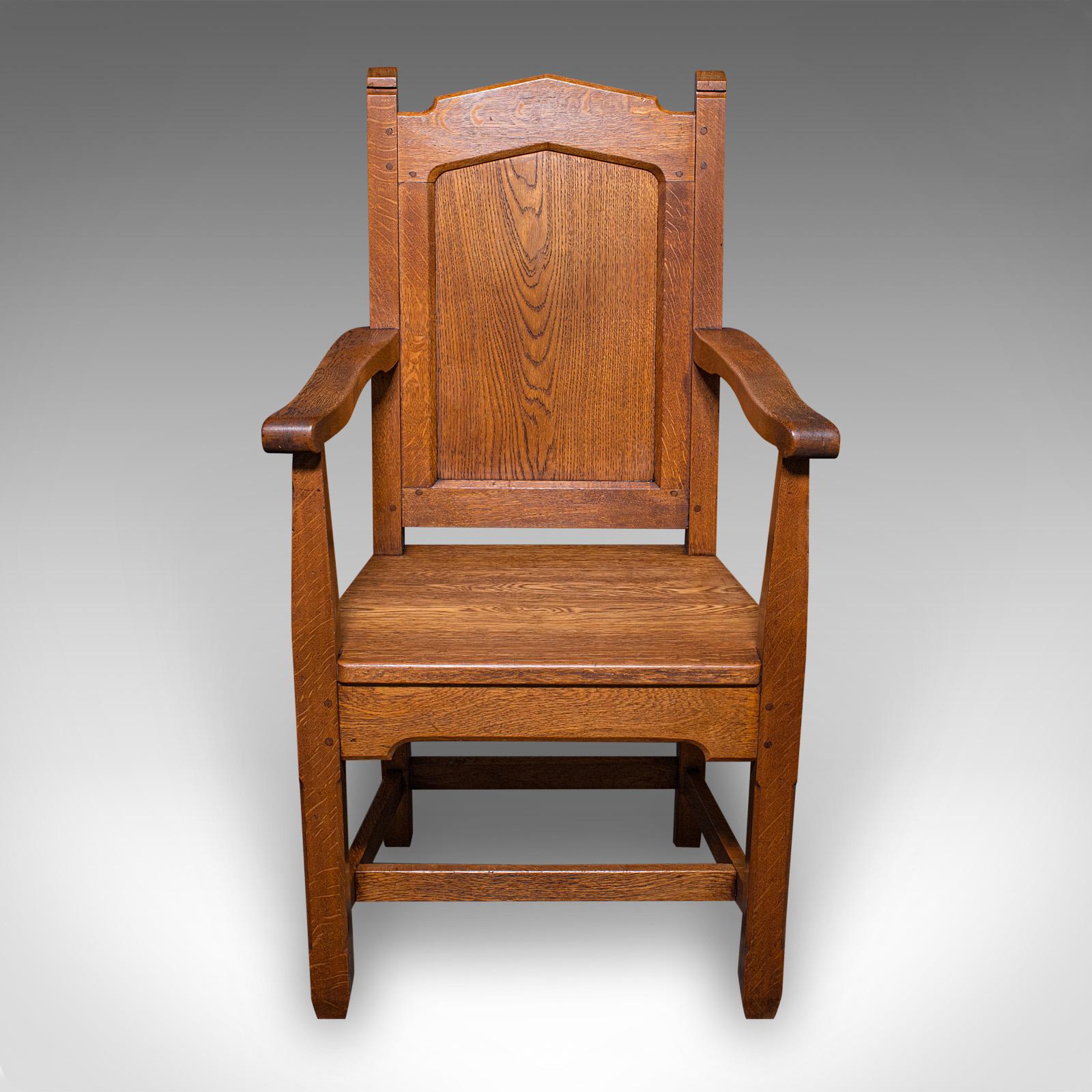 This is an antique schoolmaster's chair. An English, stout oak desk or elbow seat, dating to the Edwardian period, circa 1910.

Superb chair, of thick stocks and institutional appeal
Displays a desirable aged patina and in good order
Quality oak