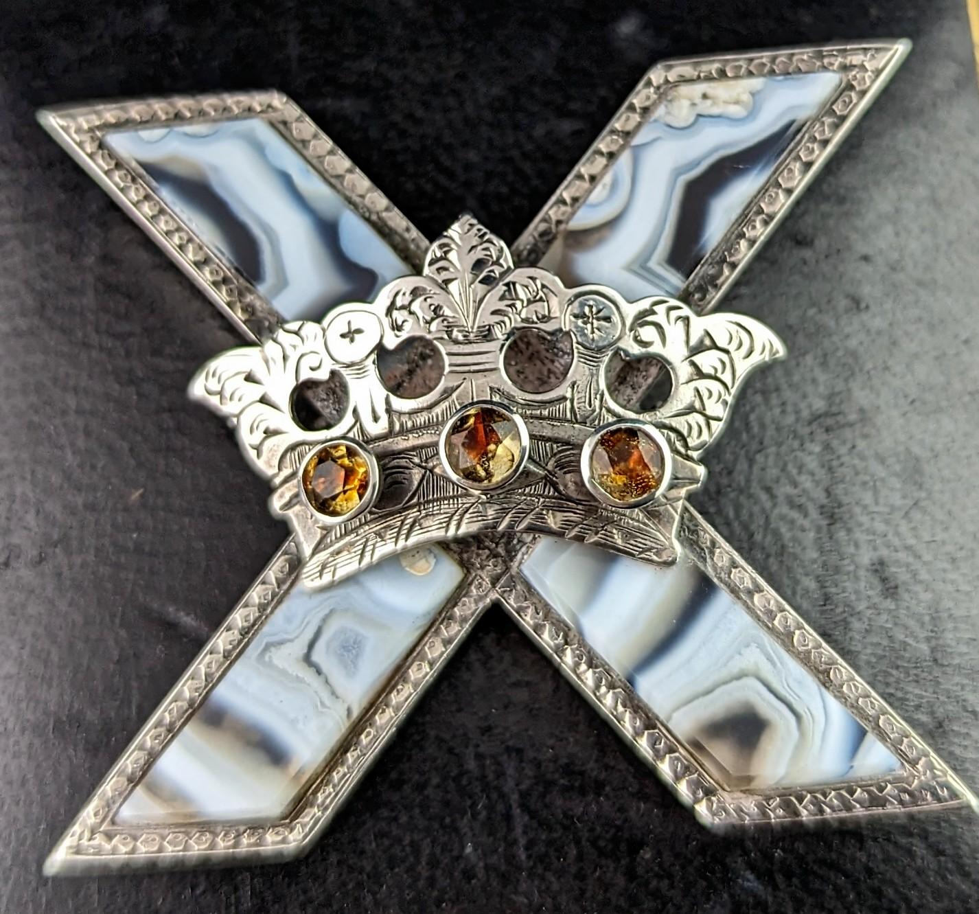 We love this unique antique, Victorian era Scottish agate and silver Saltire cross and crown brooch.

It has a large cross shape, based on the Saltire or St Andrews flag of Scotland with an applied silver crown, the crown is engraved and set with
