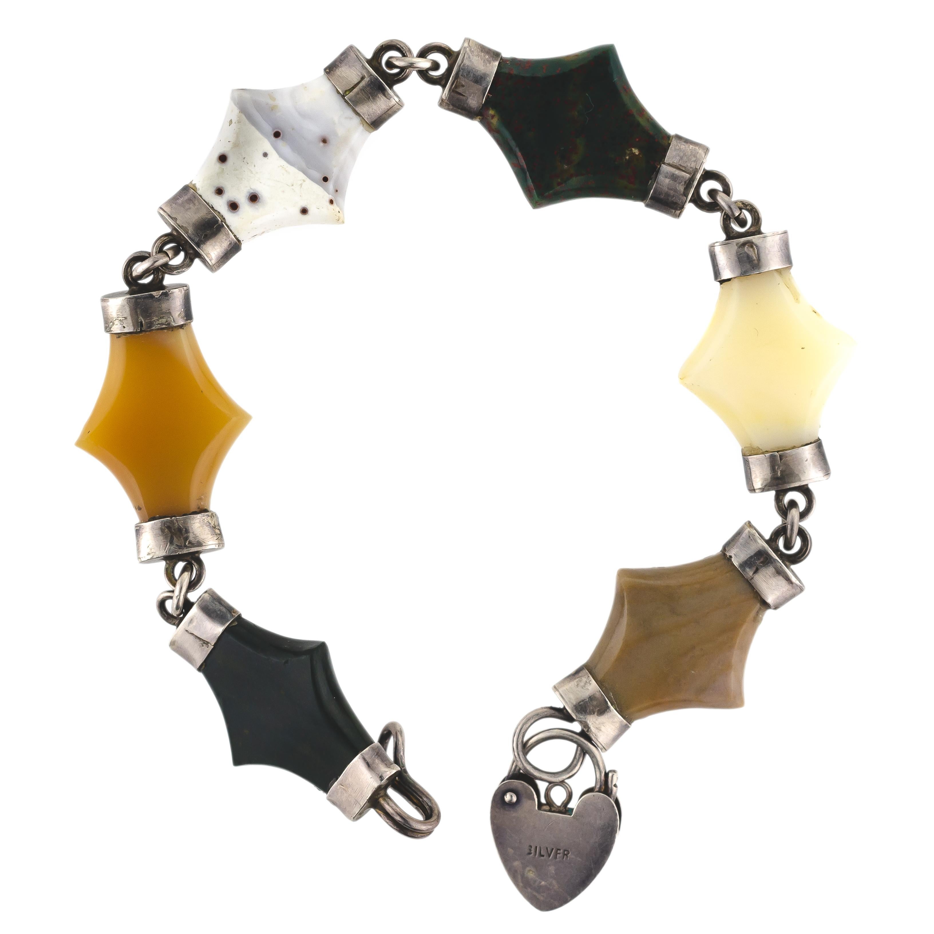 This striking Victorian Circa 1875 silver and agate flexible bracelet consisting of six (6) various colors of stylized rhombus-shaped agate stones with engraved silver caps at each end of each stone is a true beauty. A hook style silver closure with