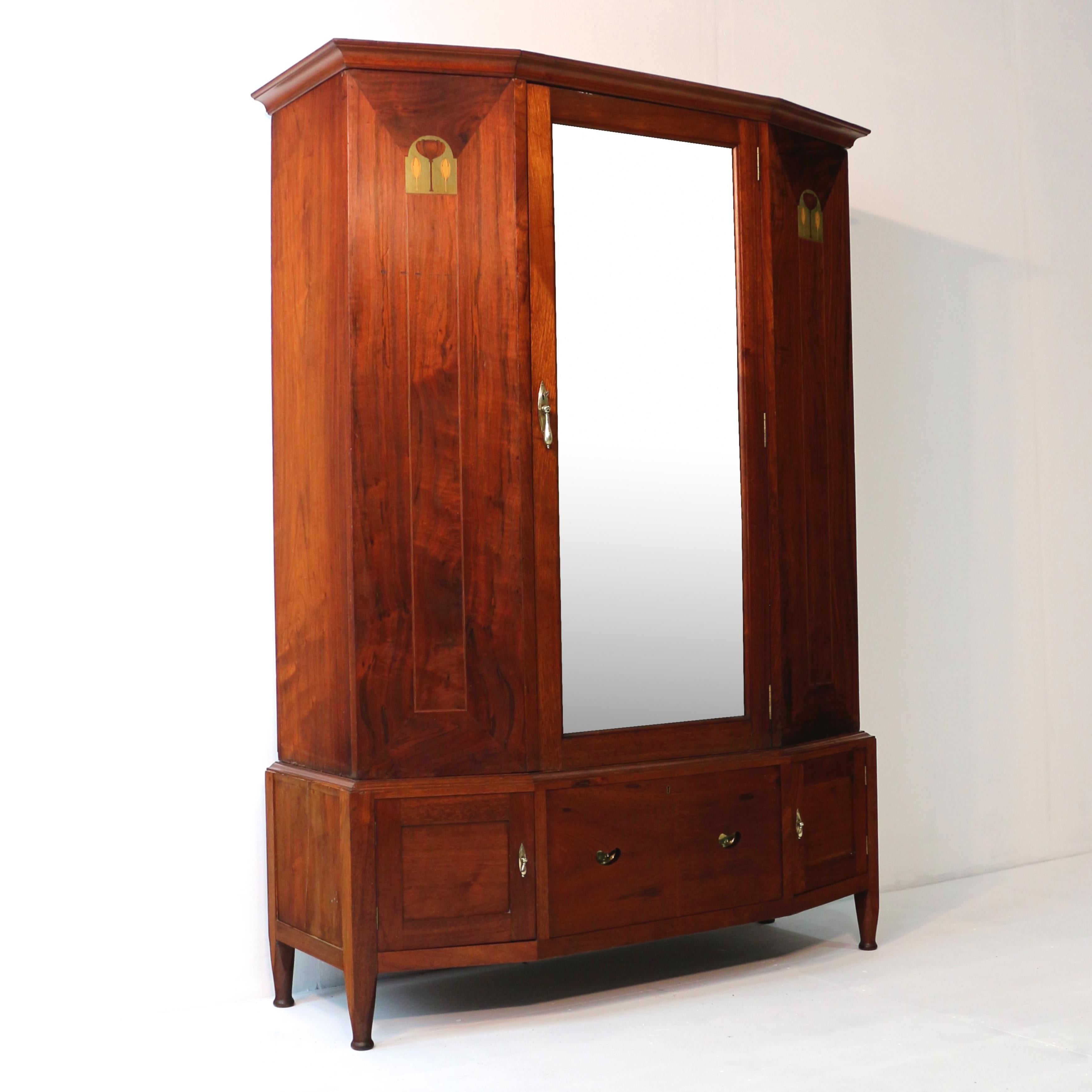 A super Glasgow School inlaid walnut wardrobe attributed to Wylie & Lochhead of Glasgow. With both Arts & Crafts and Art Nouveau influences it featured a canted D-shaped front, rich coloured well-figured solid walnut timbers and stylised flower and