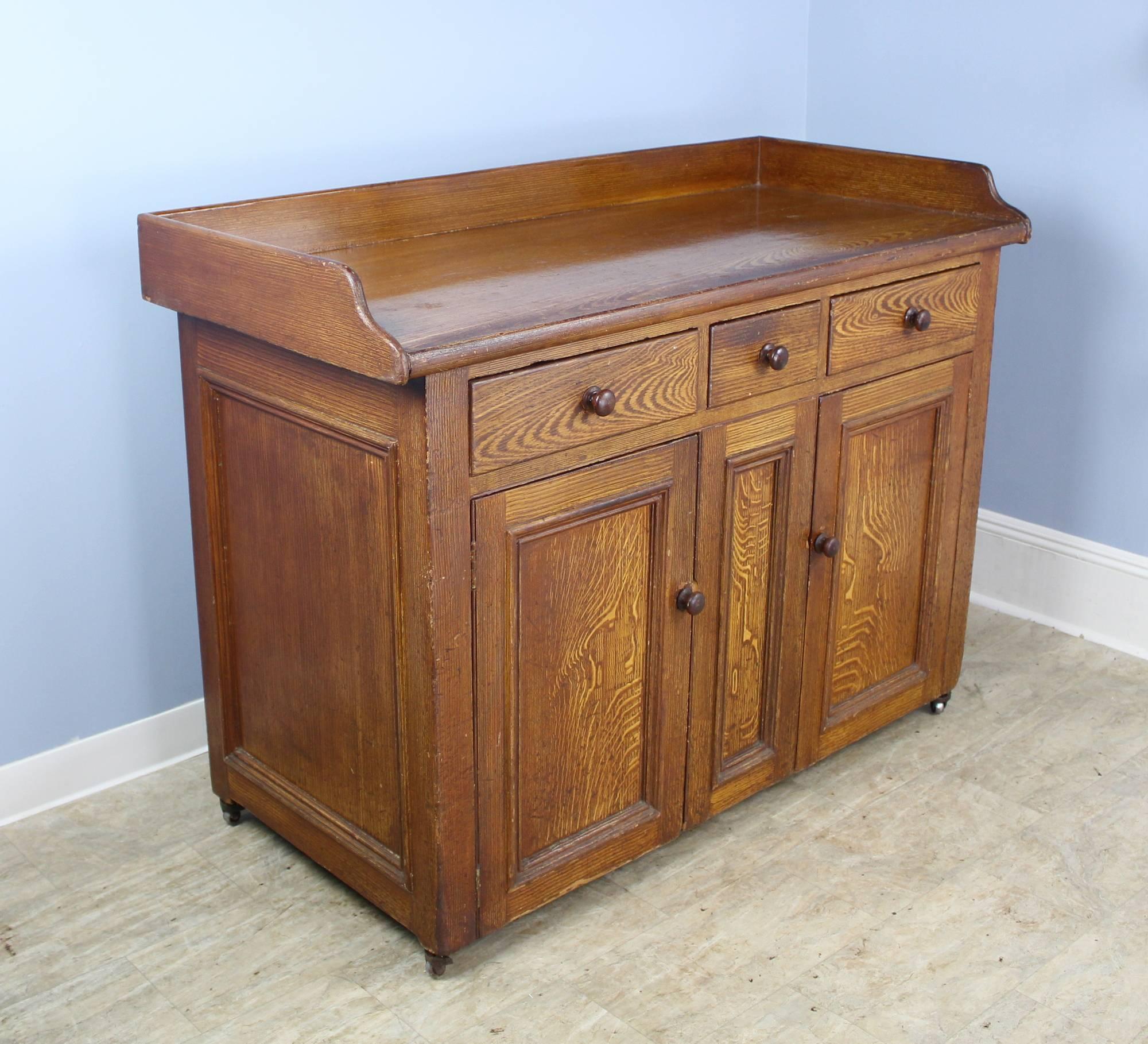 A painted Scottish pine sideboard or kitchen cupboard, hand-painted to resemble oak. This sturdy piece is generously proportioned with three roomy drawers above and large cabinets below, with one non-adjustable shelf. The piece has not been