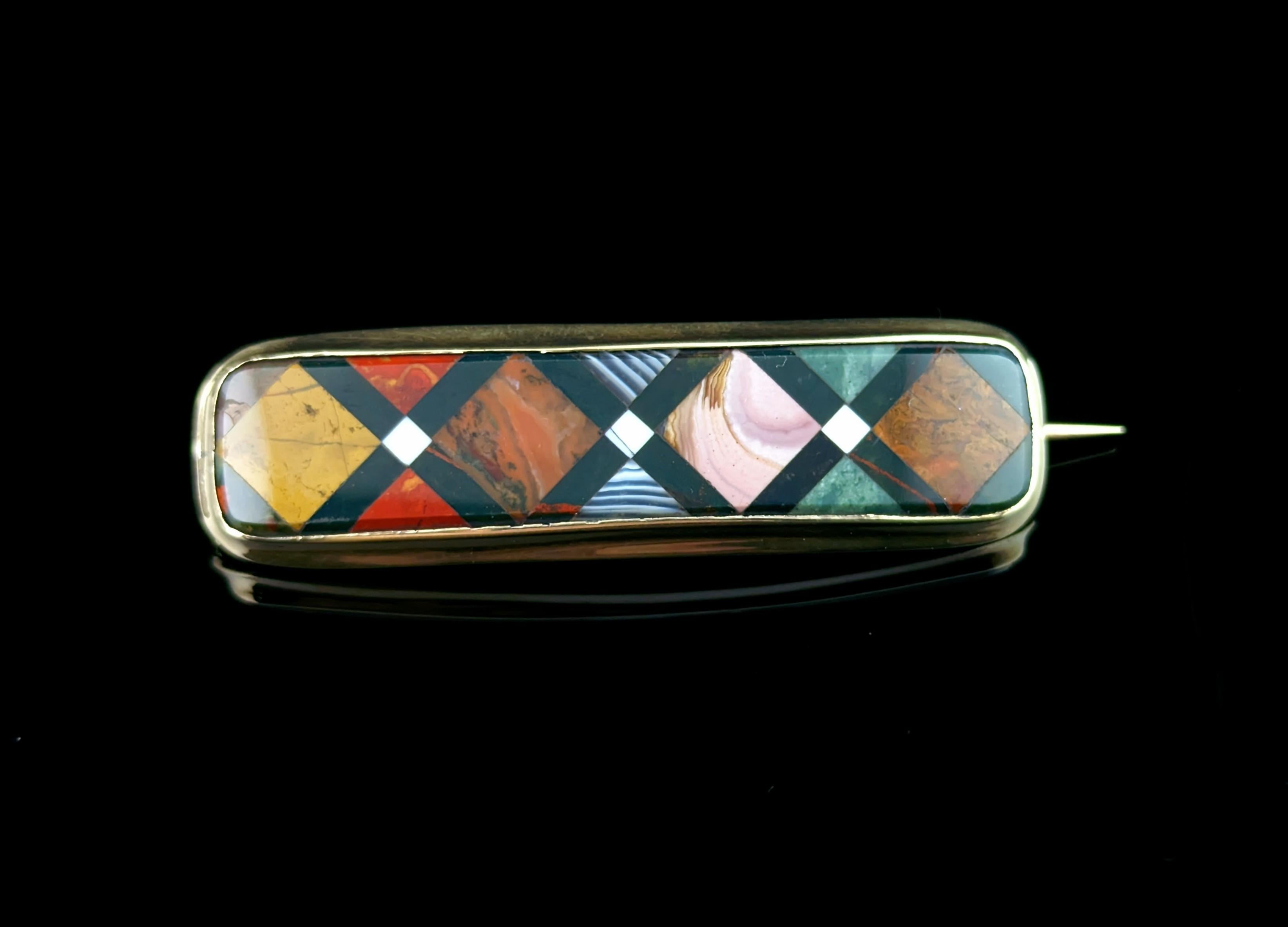 We love this unusual antique, early Victorian era Scottish pebble agate brooch.

It has a unique shape and design made up of smooth polished sections of various different agates, in a cross cross or diamond shaped design.

The warm gold bezel frame
