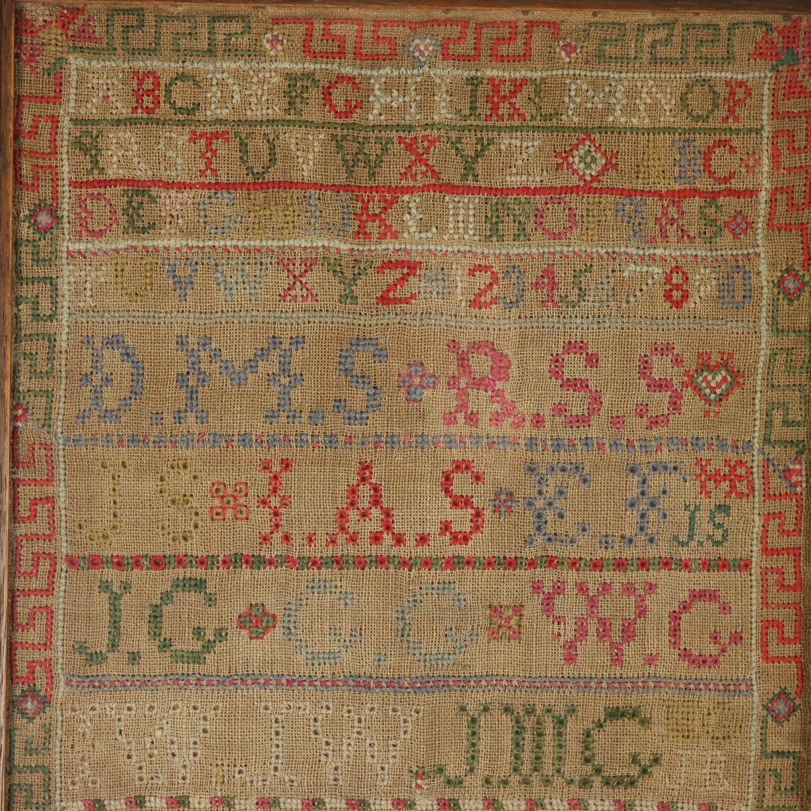 Early 19th century Scottish sampler by Mary Souter. The sampler is worked in wool and silk on a dark homespun linen ground, in cross stitch and Algerian eye. Greek key border. Colours red, yellow, dark brown, white, black, pink, green and blue.