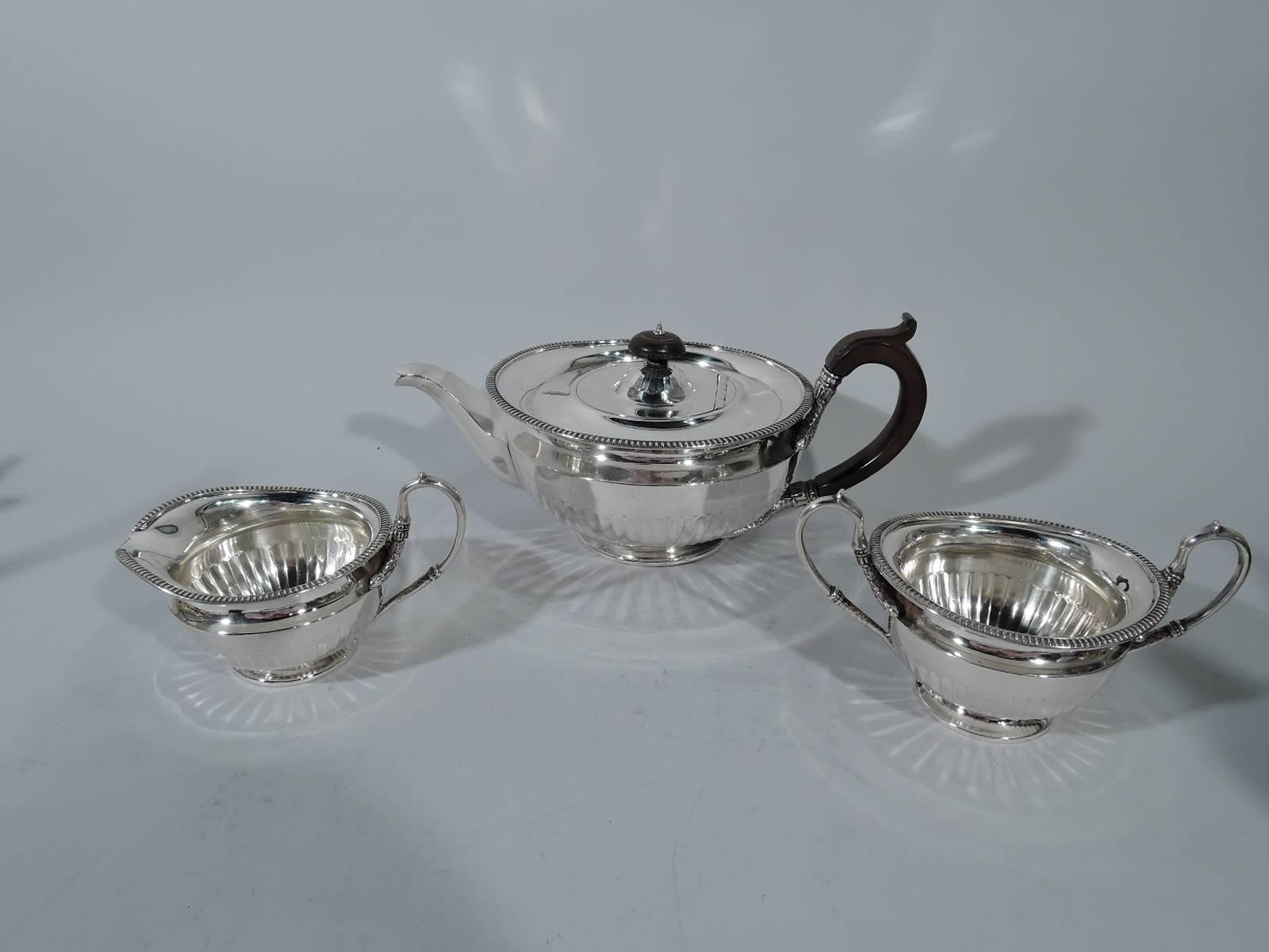 Regency Revival sterling silver tea set. Made by Hamilton & Inches in Edinburgh in 1923. This set comprises teapot, creamer, and sugar. All: Curved and tapering sides on raised foot. Gardrooned rim. Shallow and shimmering half fluting. Capped