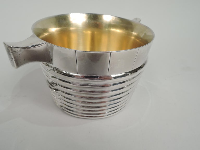 Victorian sterling silver butter tub. Made by Hamilton & Inches in Edinburgh in 1883. Round with tapering sides. Lobed rings; at top tooled faux wood slats. Tapering and upturned side handles. Interior gilt washed. Fully marked. Weight: 11 troy