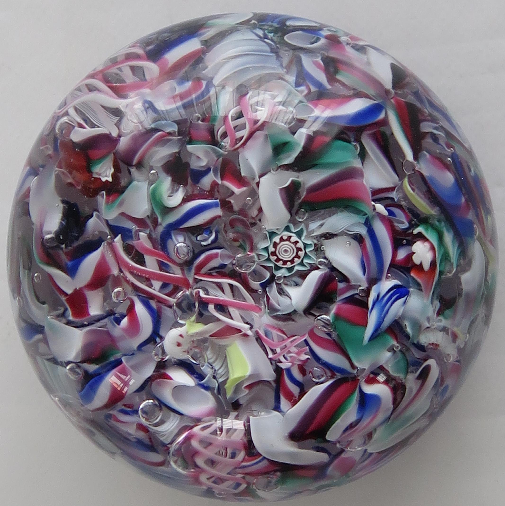 This is a fine example of a scrambled Glass Paperweight by the New England Glass Company, dating to 1852.

The weight includes latticinio twists and various different millefiori canes. The glass is quite clear with no scratches or nicks on the