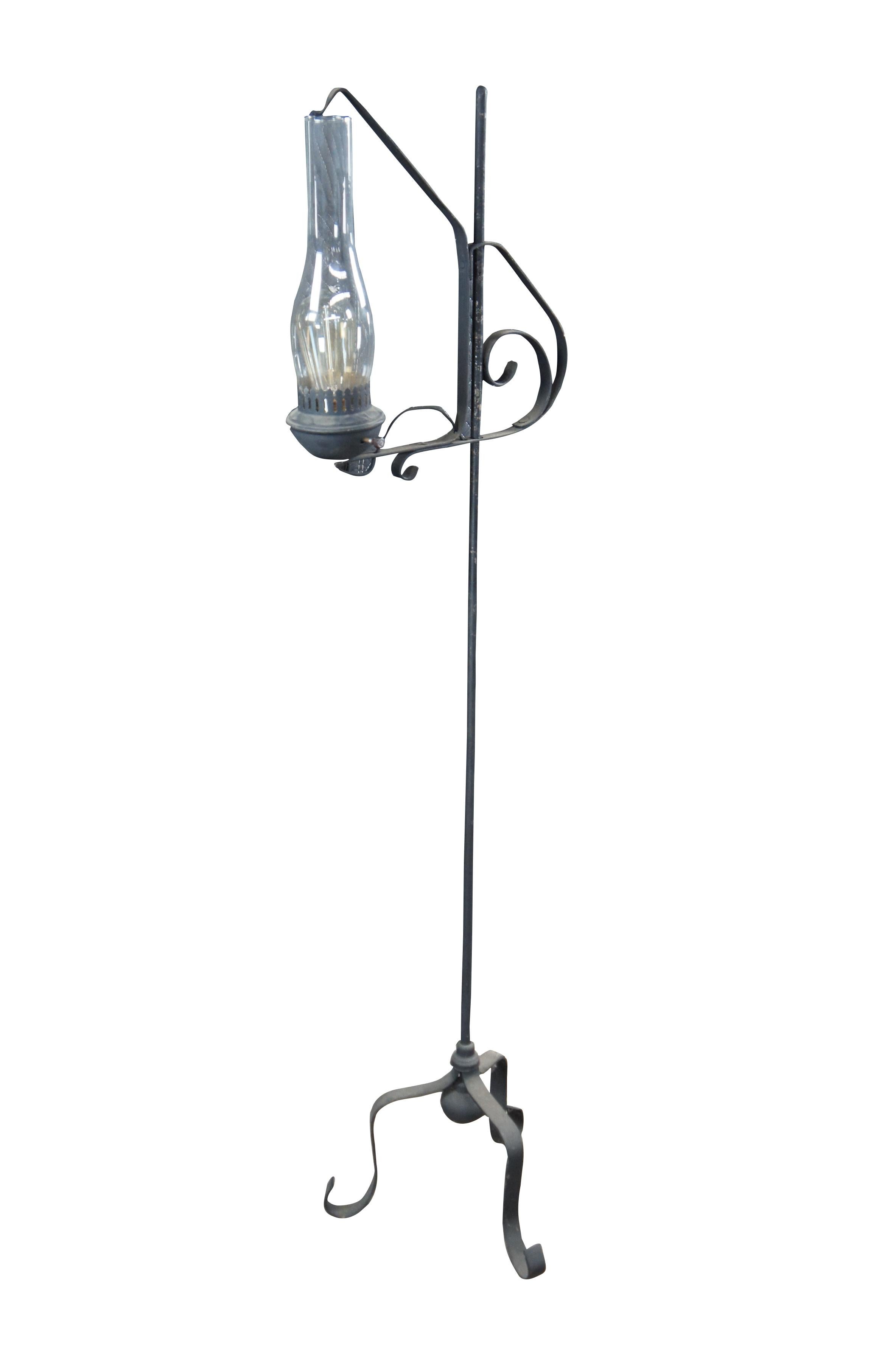 Primitive antique Spanish Revival Colonial style converted candle stand.  Features adjustable hurricane lantern over a wrought iron rod with tripod scrolled base.  The lantern would have originally operated with the use of a candle and was later