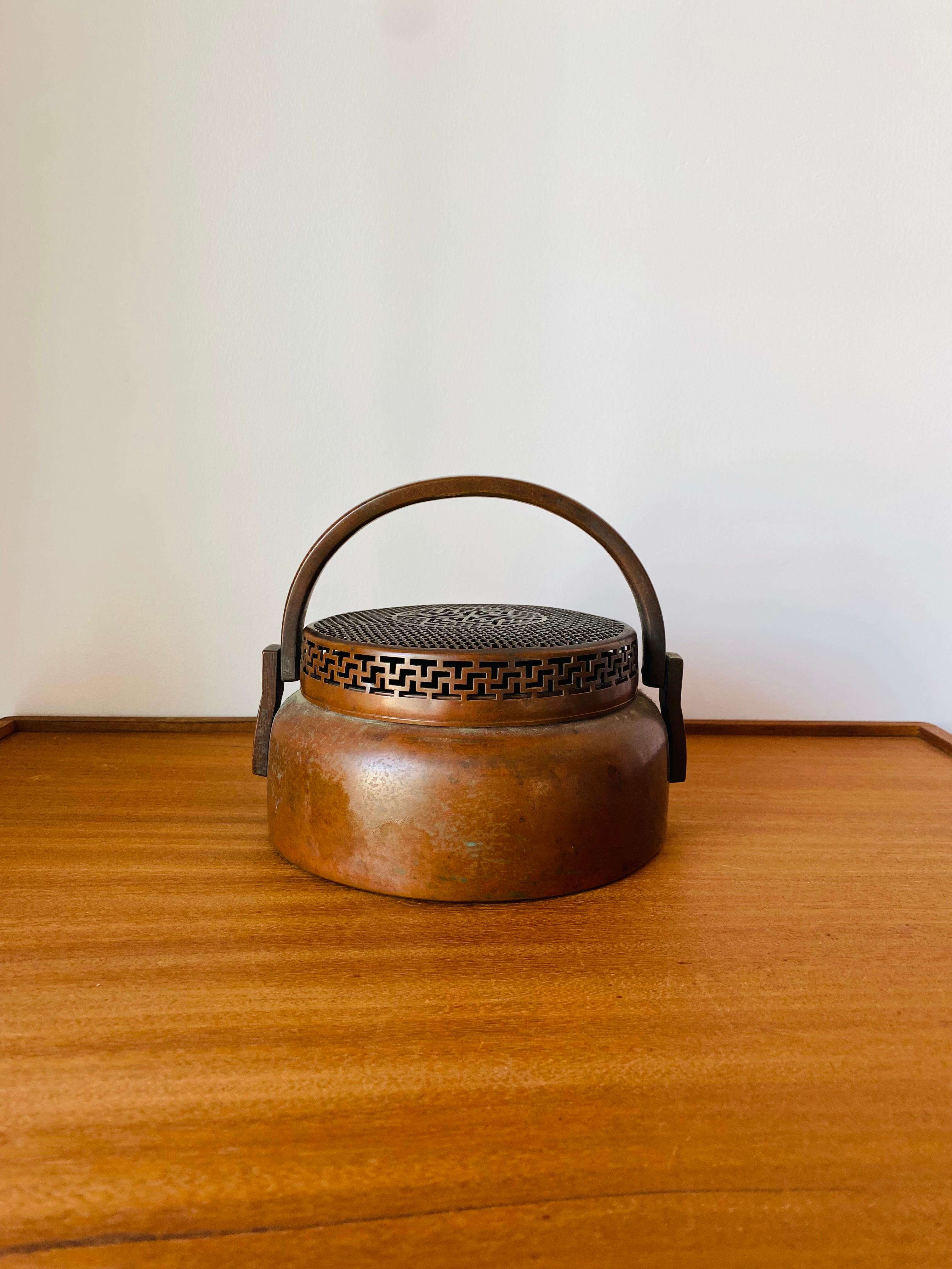 Artistically and visually stunning early 19th Century piece of copper work.  This intricate piece is full of detail.  The compressed globular body rises to a waisted neck which is complemented by the intricate lattice like lid. A solid handle