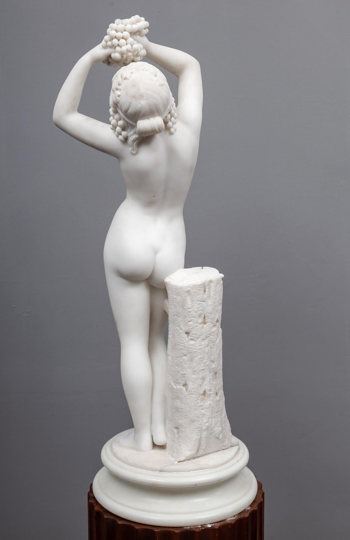 A beautifully carved antique statuary Carrara marble sculpture of Aphrodite. Depicted in the nude, holding a bunch of grapes and standing beside a tree stump.

Aphrodite is an ancient Greek goddess associated with love, beauty, pleasure, passion