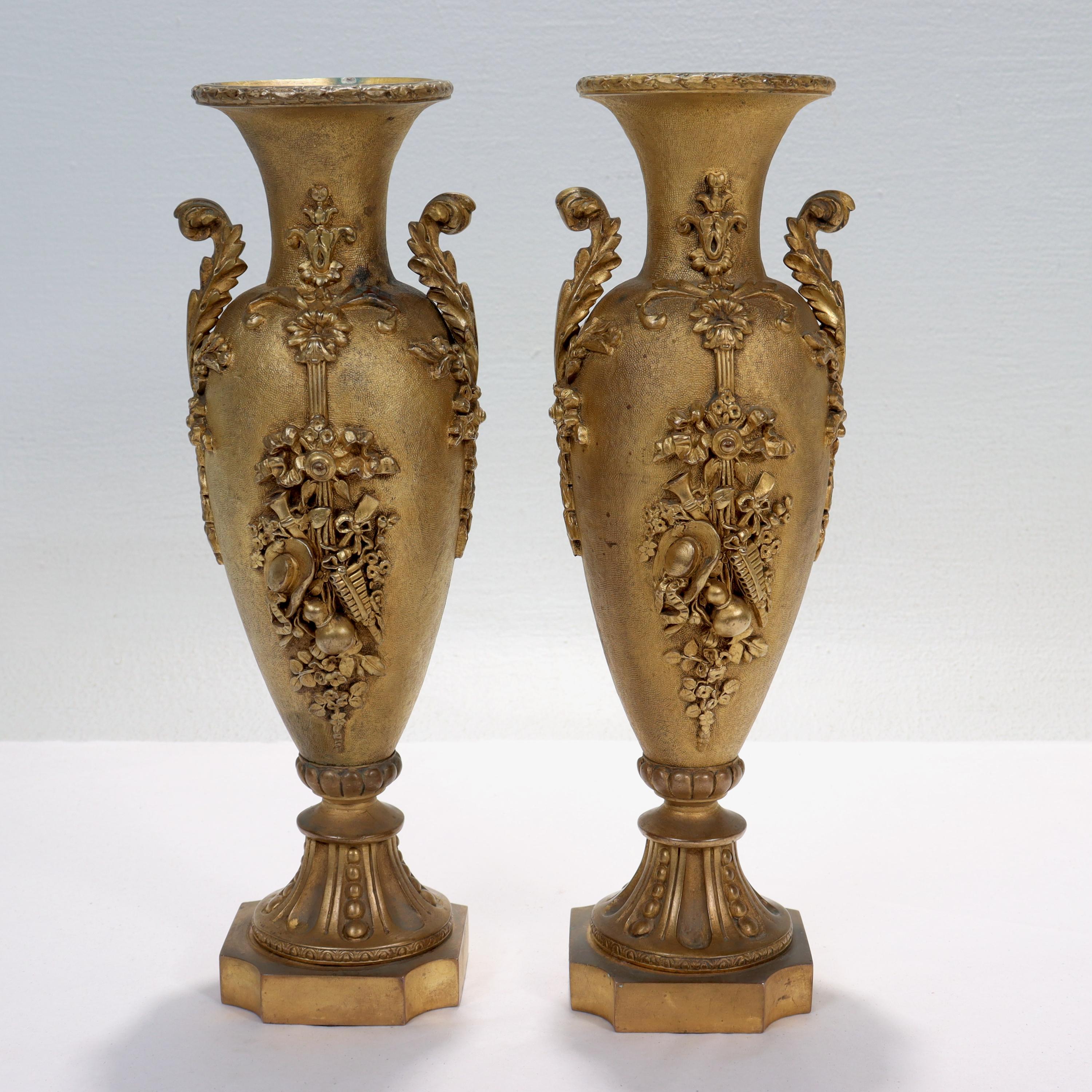 A fine pair of antique French gilt bronze vases.

Decorated with an assembly of musical instruments, a gourd, and even a hat. 

Extremely solid and finely cast, these urns or vases are much heavier in the hand than one would expect.

Simply