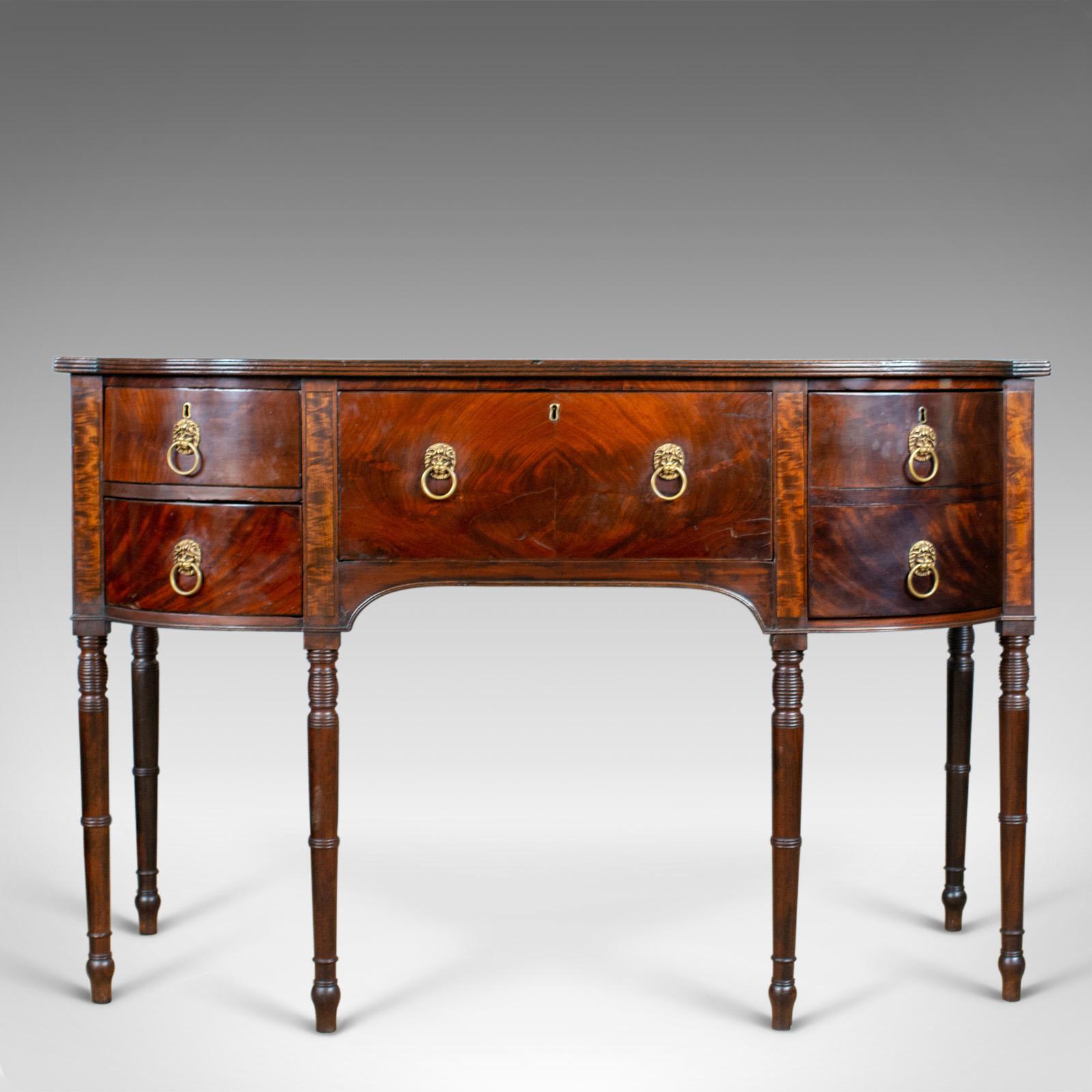 This is an antique secretaire, bow-fronted sideboard. An English, Georgian server with desk drawer in flame mahogany and dating to the late 18th century, circa 1790.

Rare to find in the secretaire configuration
Select flame mahogany with grain