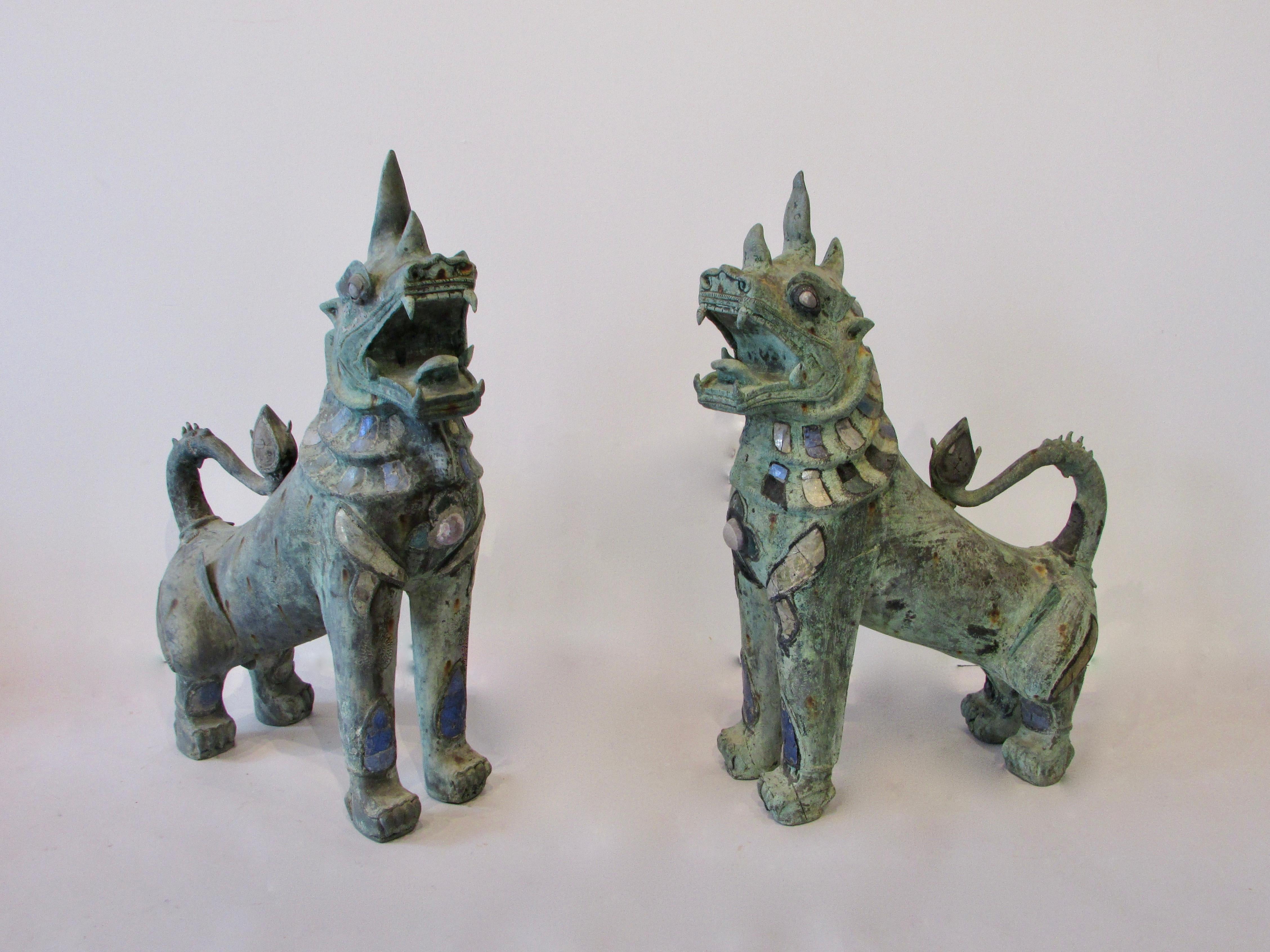 Pair of antique bronze Thai foo lions. They are a right and left pair. Heads are turned in opposing direction. Bodies are embellished with semi precious or mineral stones. Large ferocious old and impressive.