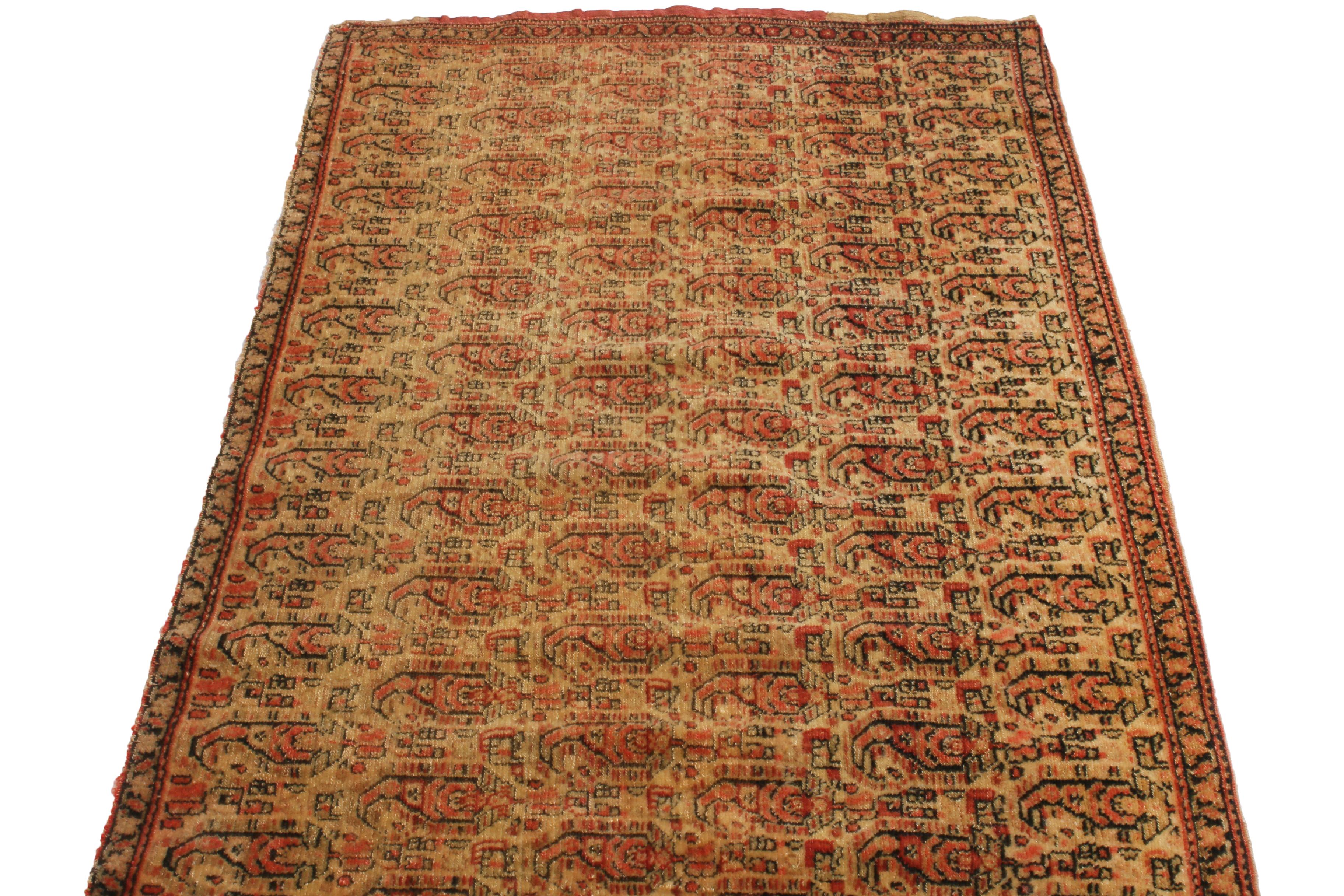Originating from Persia between 1880-1900, this antique Senneh Persian rug is home to an inviting, repetition of traditional Boteh paisley patterns, complemented by lively carnation pink and red colorways against the luminous beige background.